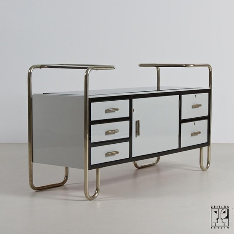 This striking avant-garde chest of drawers, a masterpiece inspired by the German Modernist Bauhaus style, was crafted in 1935. It exemplifies a fusion of robust elegance, a hallmark of the Bauhaus era. The incorporation of polished steel gives the