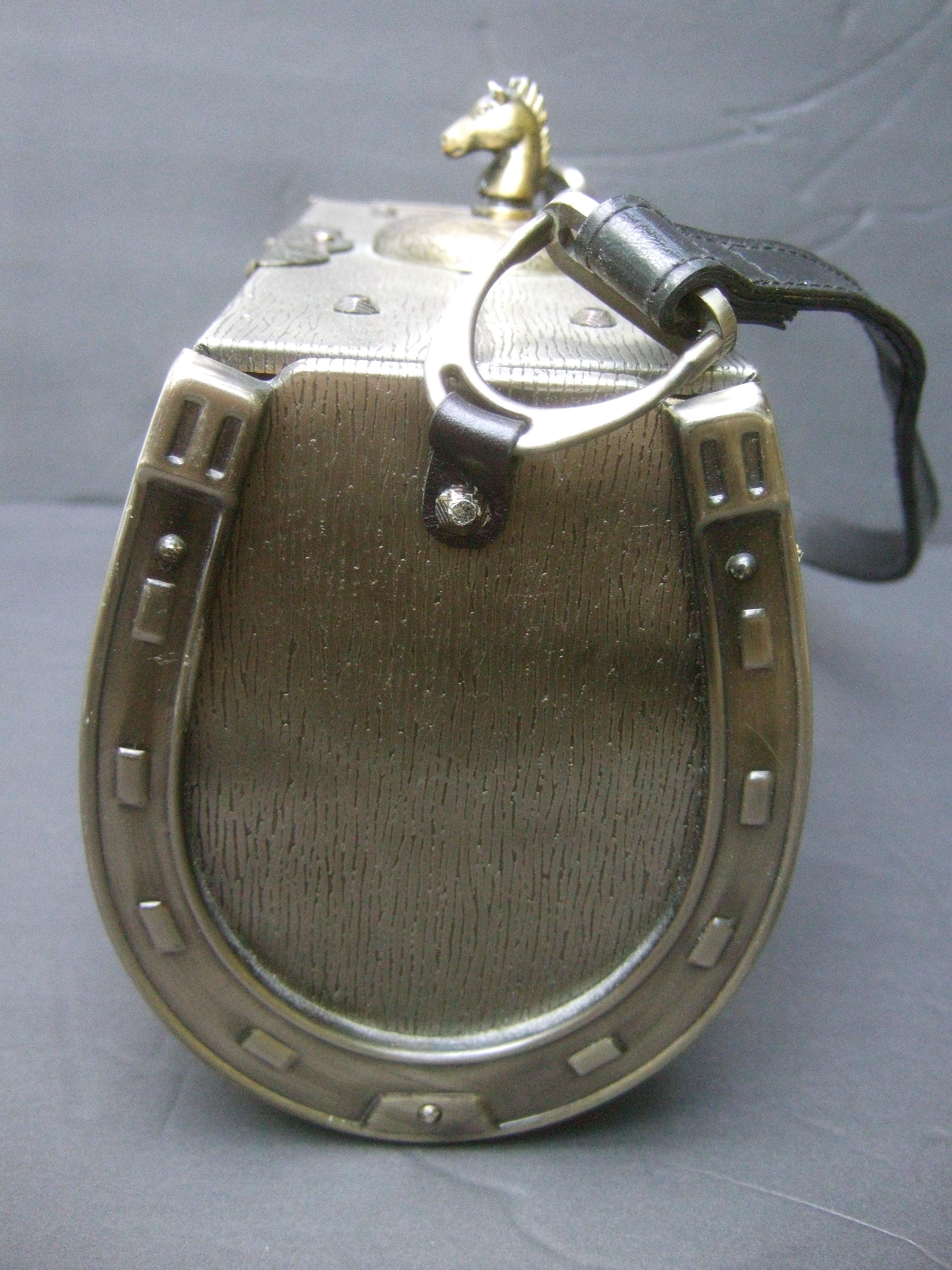 Avant-garde pewter mixed metal equine theme box purse c 1970s
The unique metal box purse is adorned with a burnished brass metal horse head mounted on top of the lid cover 

All sides of the cylinder trunk purse are constructed with pewter tone