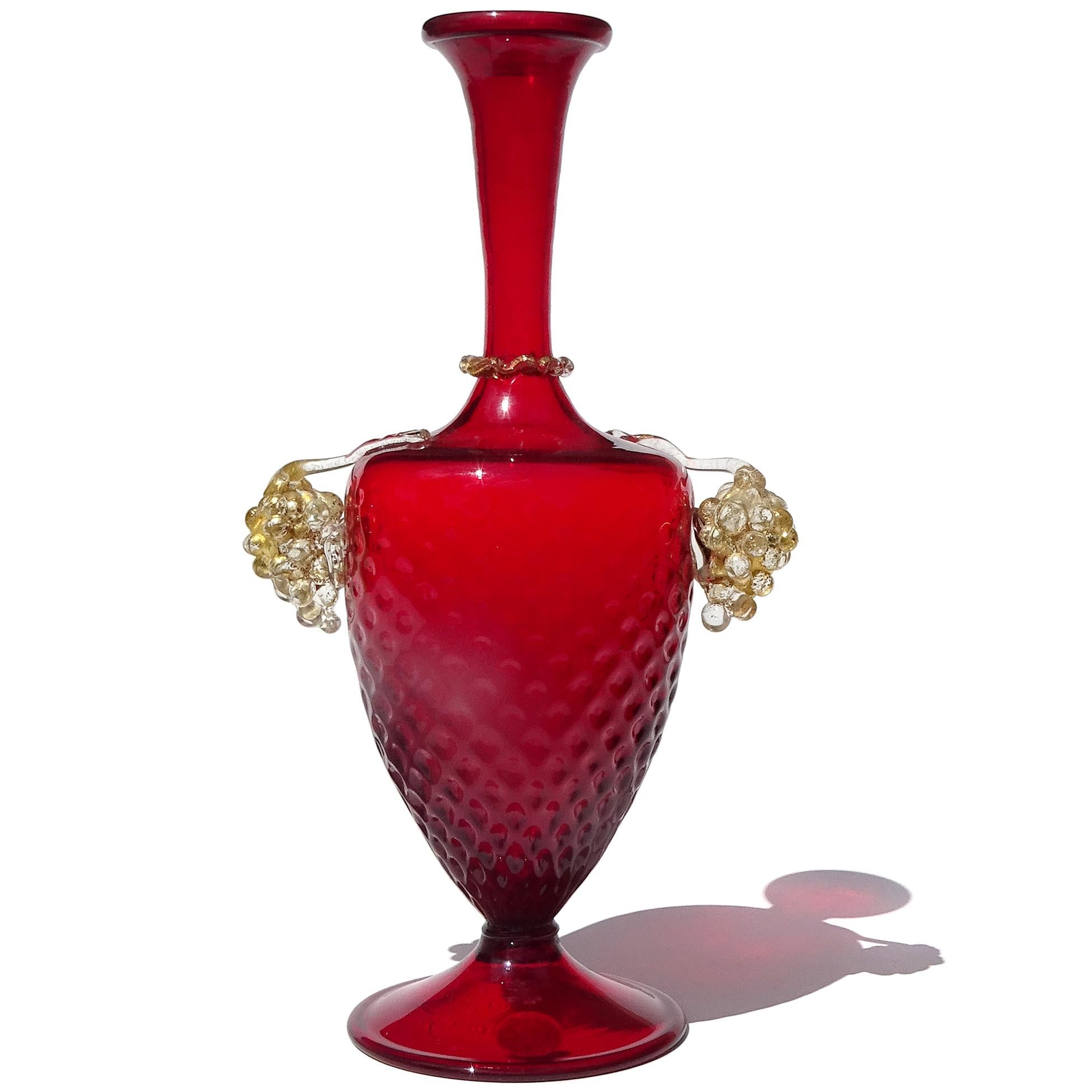 Beautiful and elegant, vintage Murano hand blown ruby red and clear glass with gold grape decoration, Italian art glass footed flower vase. The piece is documented to the Arte Vetraria Muranese (A.Ve.M.) company, and has an original label