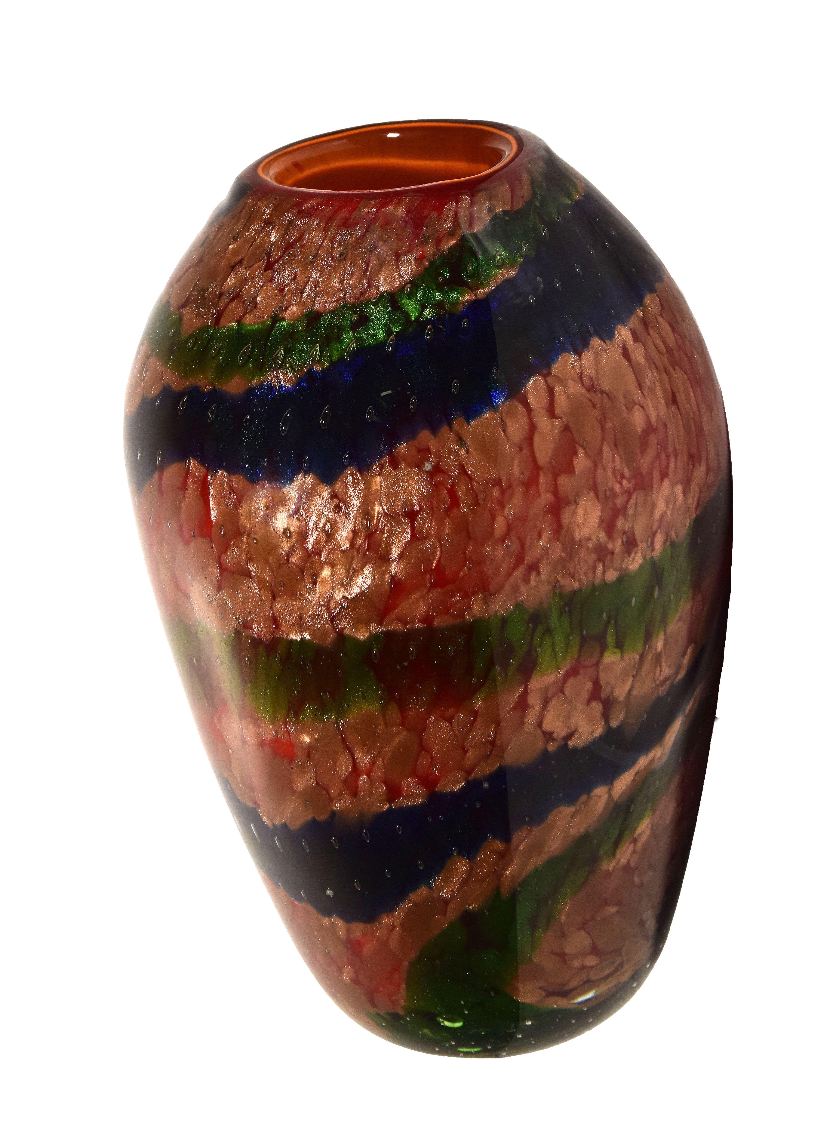 You are admiring an Aventurine vase, a precious decorative object manufactured very likely by Aureliano Toso in the 1960s.

Beautiful transparent vase in aventurine, layered in red and decorated with green and blue bands. 

Dimensions: cm 14 x
