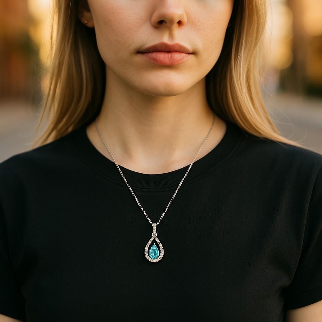 Il Ciondolo Avery è un pezzo raffinato e luminoso, caratterizzato da uno splendido topazio blu svizzero naturale a forma di pera incastonato nell'oro bianco 10 carati, accentuato da scintillanti diamanti naturali rotondi. Abbinato a una catenina da