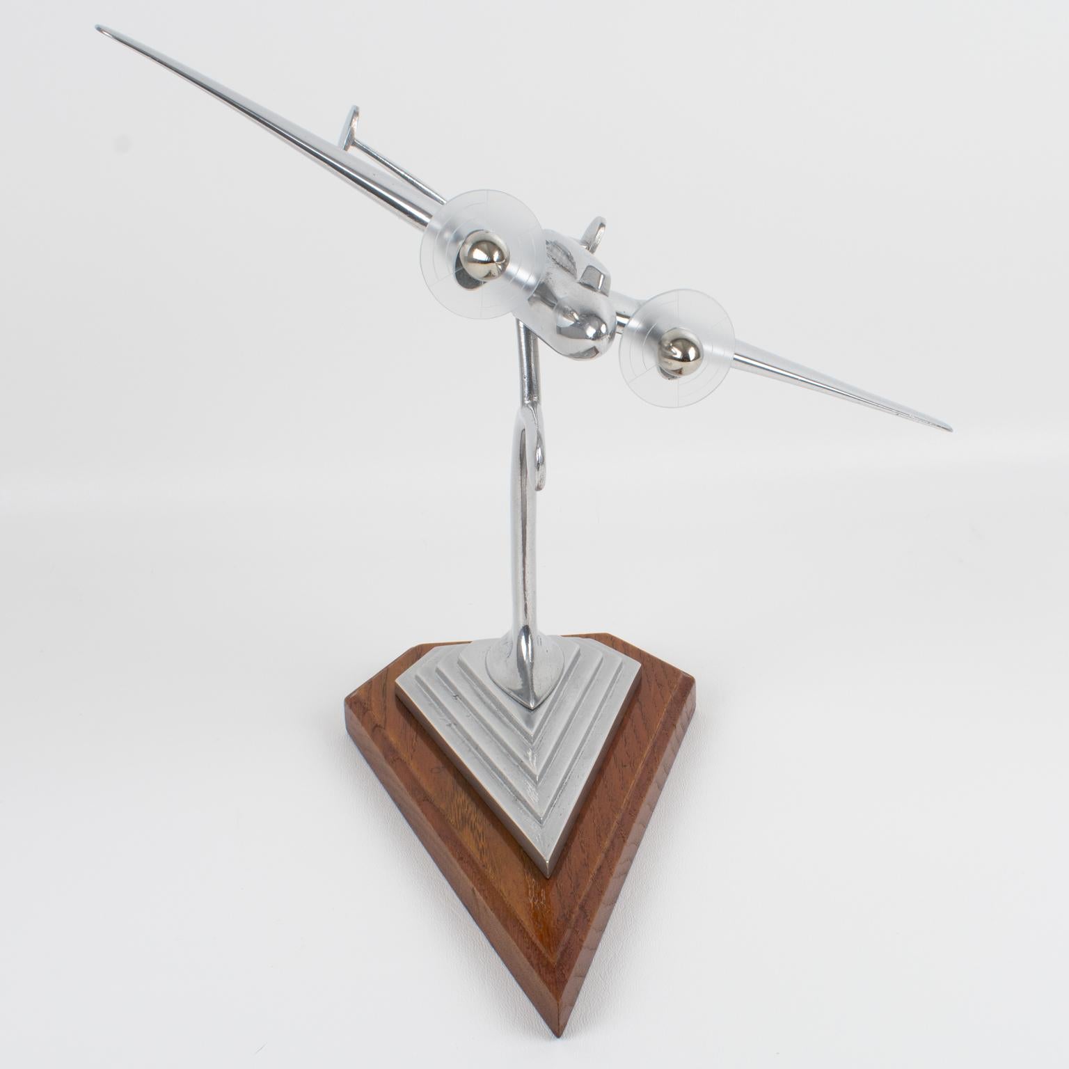 Elegant French airplane model mounted on a wood plinth. This nice sculptural model airplane is made with cast aluminum and has two Lucite propellers. Standing on a geometric raised stepped plinth in varnish wood with aluminum shaped arm. There is no