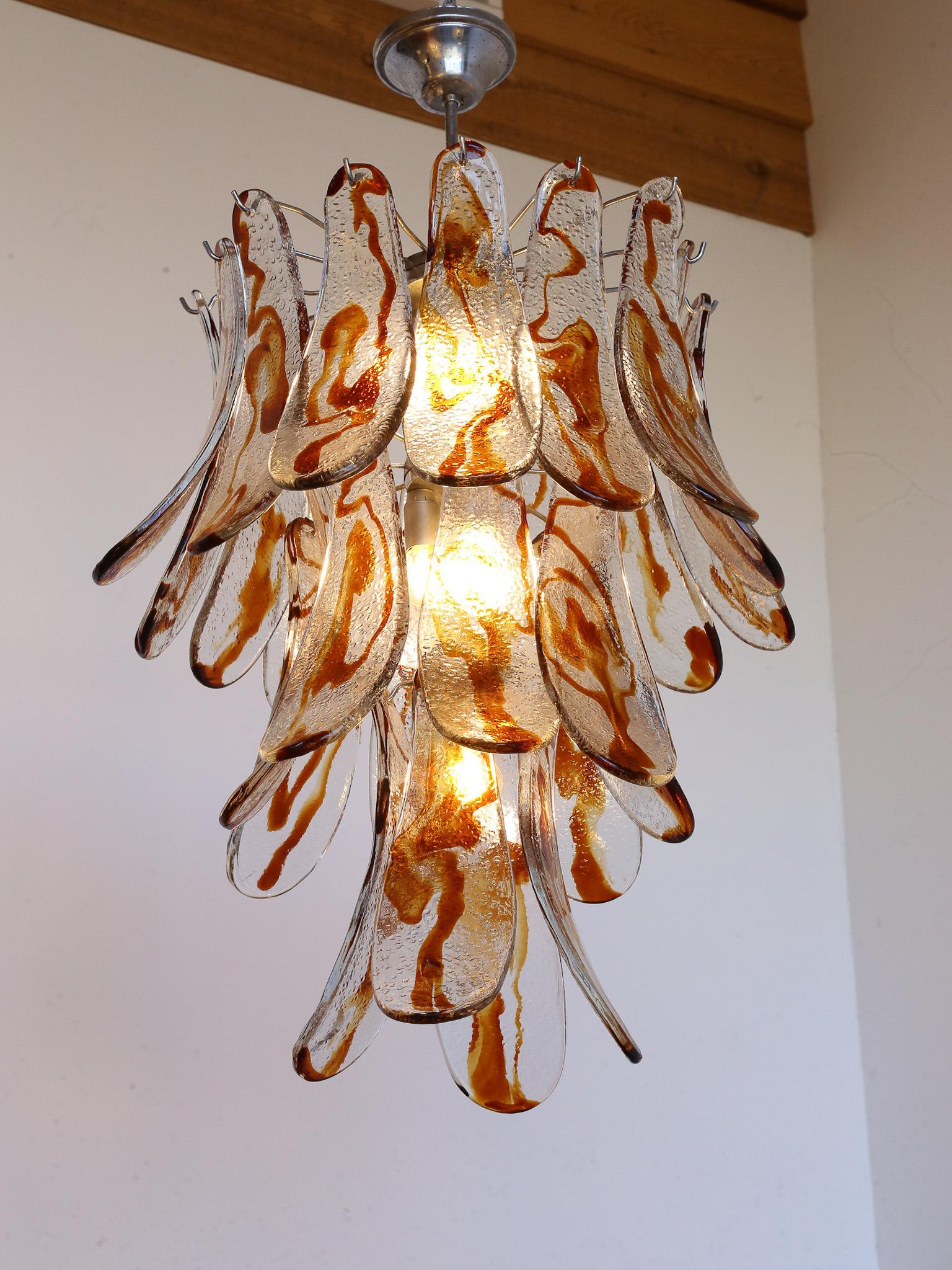 Amber Murano Glass and chrome pendant light with the total of twenty seven pieces, each saddle it's around 1 cm thick  

AV Mazzega, also known as Vetreria Mazzega, is an esteemed Italian glass manufacturer located in Murano, an island near Venice