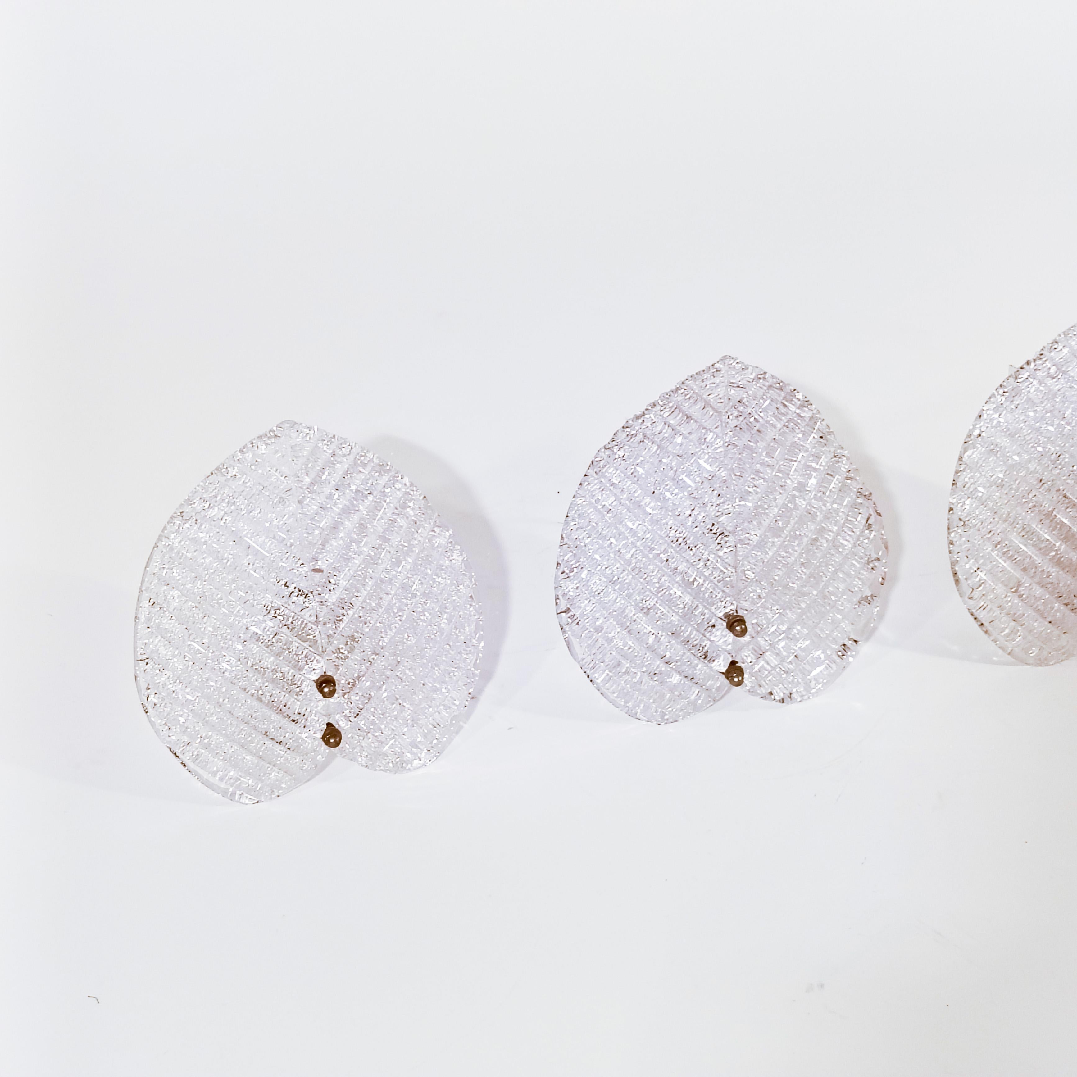 Appliques murales en verre de Murano faites à la main par AV Mazzega, années 1970, ensemble de 3. Chaque lampe est composée d'un morceau de verre de Murano en forme de feuille attaché à une structure en métal laqué blanc par deux écrous en laiton.