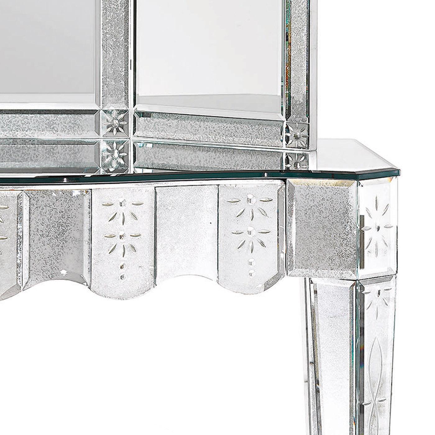 The Avogaria make-up desk of the Murano Collection has a distinct Venetian inspiration. The structure is made of wood with a silver leafed finish and the four tapered legs. The top and back-side are made of beveled glass with a medium antique