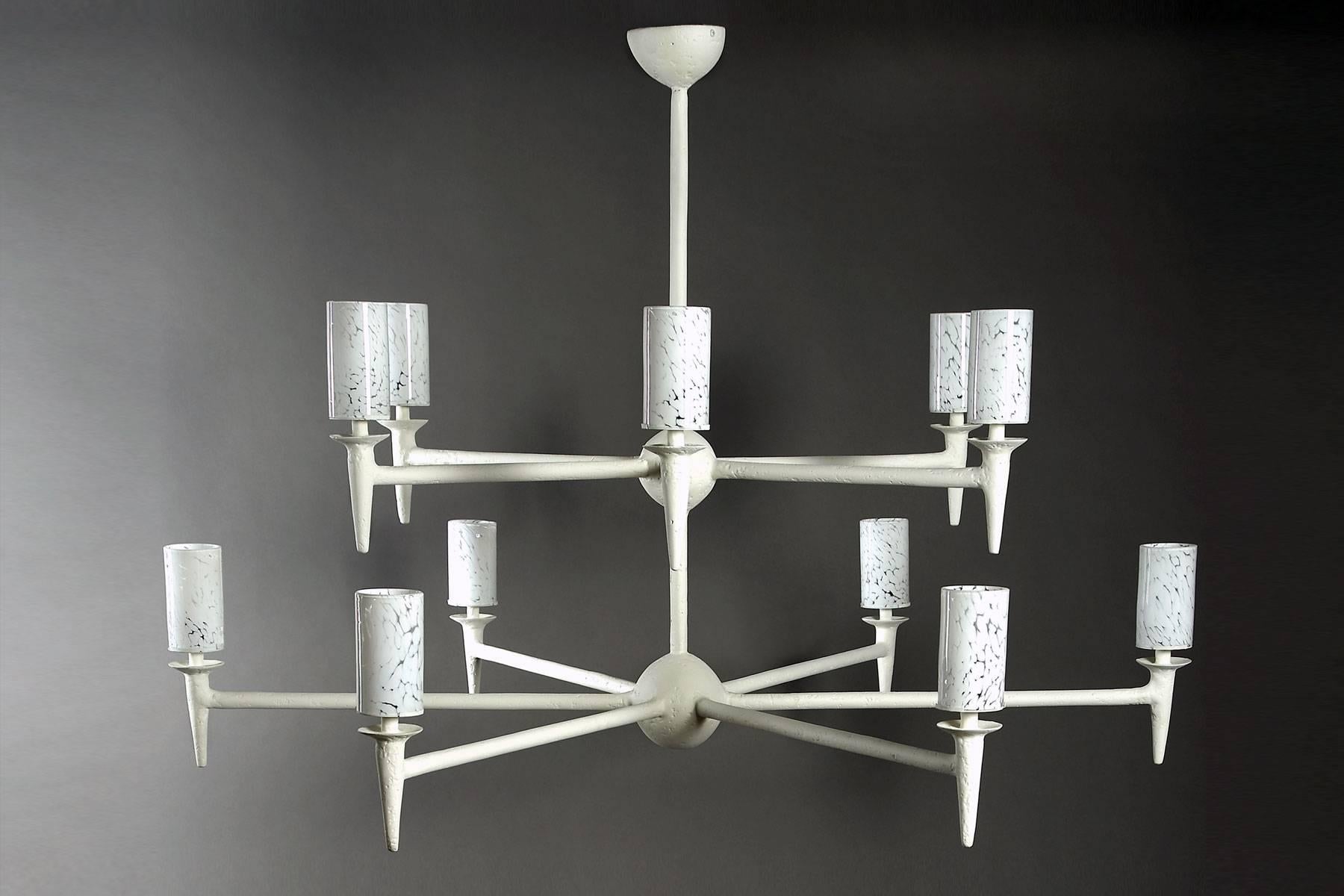 Ce grand lustre, qui fait partie de notre collection de luminaires en plâtre de Paris, peut être réalisé sur mesure. Ce modèle comporte 12 bras sur deux niveaux. La lumière est diffusée à travers les cylindres en verre soufflé à la main, qui donnent