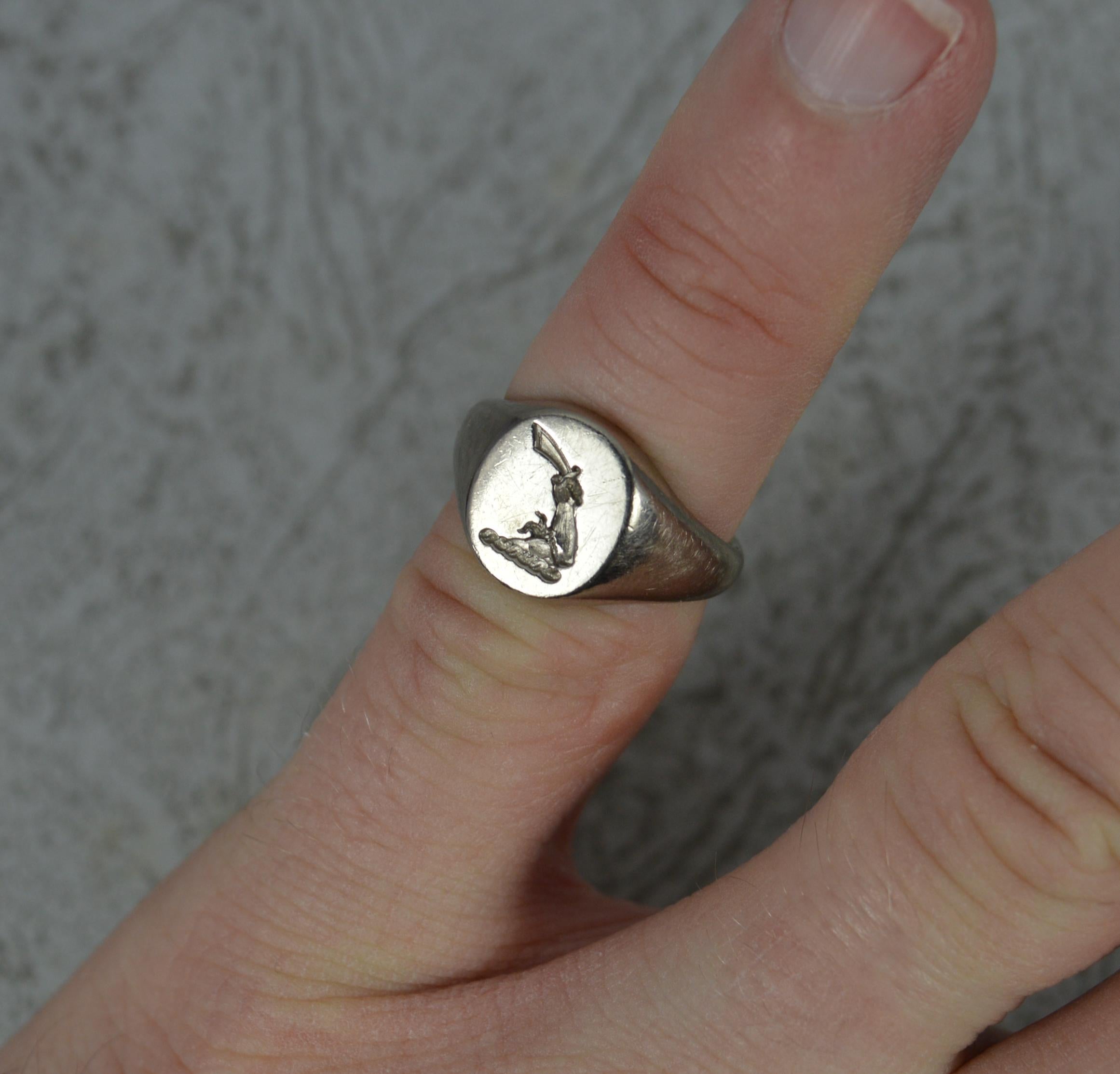 A superb contemporary signet ring.
Solid 18 carat white gold example.
10.3mm x 8.5mm oval shaped signet with a deeply carved intaglio seal of an armoured hand holding a sword or dagger.

CONDITION ; Very good. Clean and solid band. Crisp intaglio.