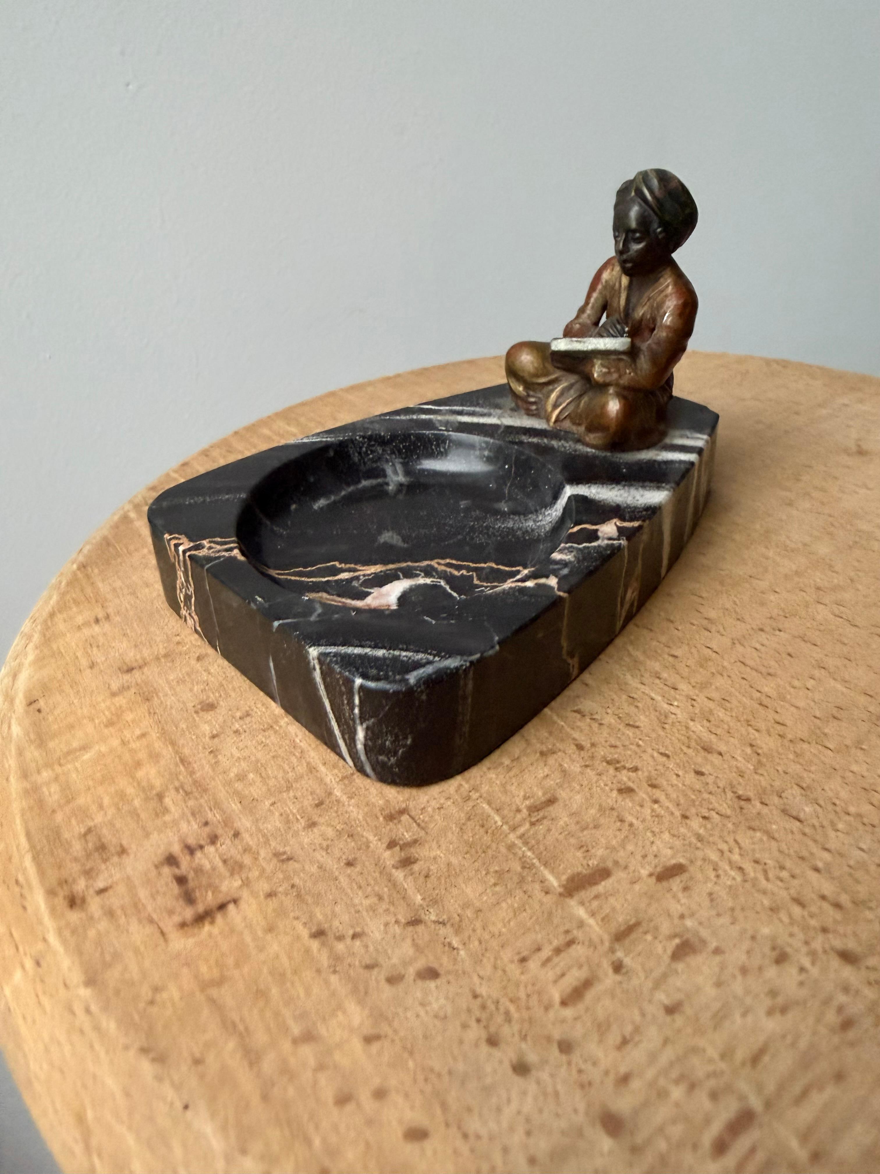 Giovane scrittore in bronzo di Vienna su marmo nero, un momento di tranquilla creazione.

Questo bronzo di Vienna dell'inizio del XX secolo cattura una scena splendidamente intima: una figura seduta, con le gambe piegate sotto di sé, che tiene un