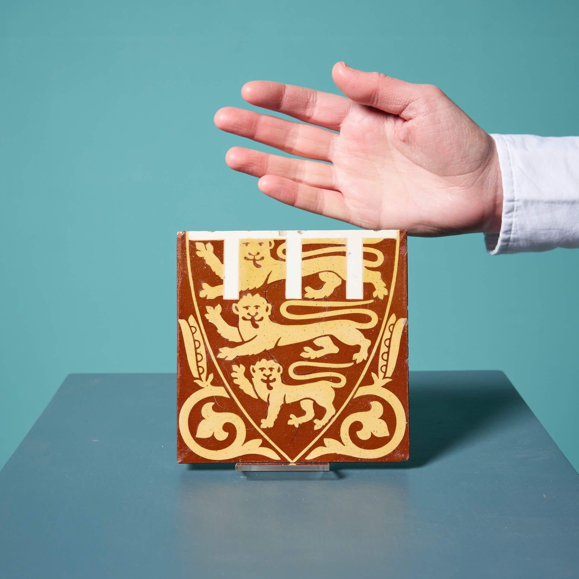 Un ancien carreau à l'encaustique émaillé de A.W.N Pugin par Minton & Coates représentant les armoiries du Prince de Galles.

Cette tuile carrée de 5 pouces est ornée de trois lions passant dans un écu héraldique et flanquée de gousses de graines