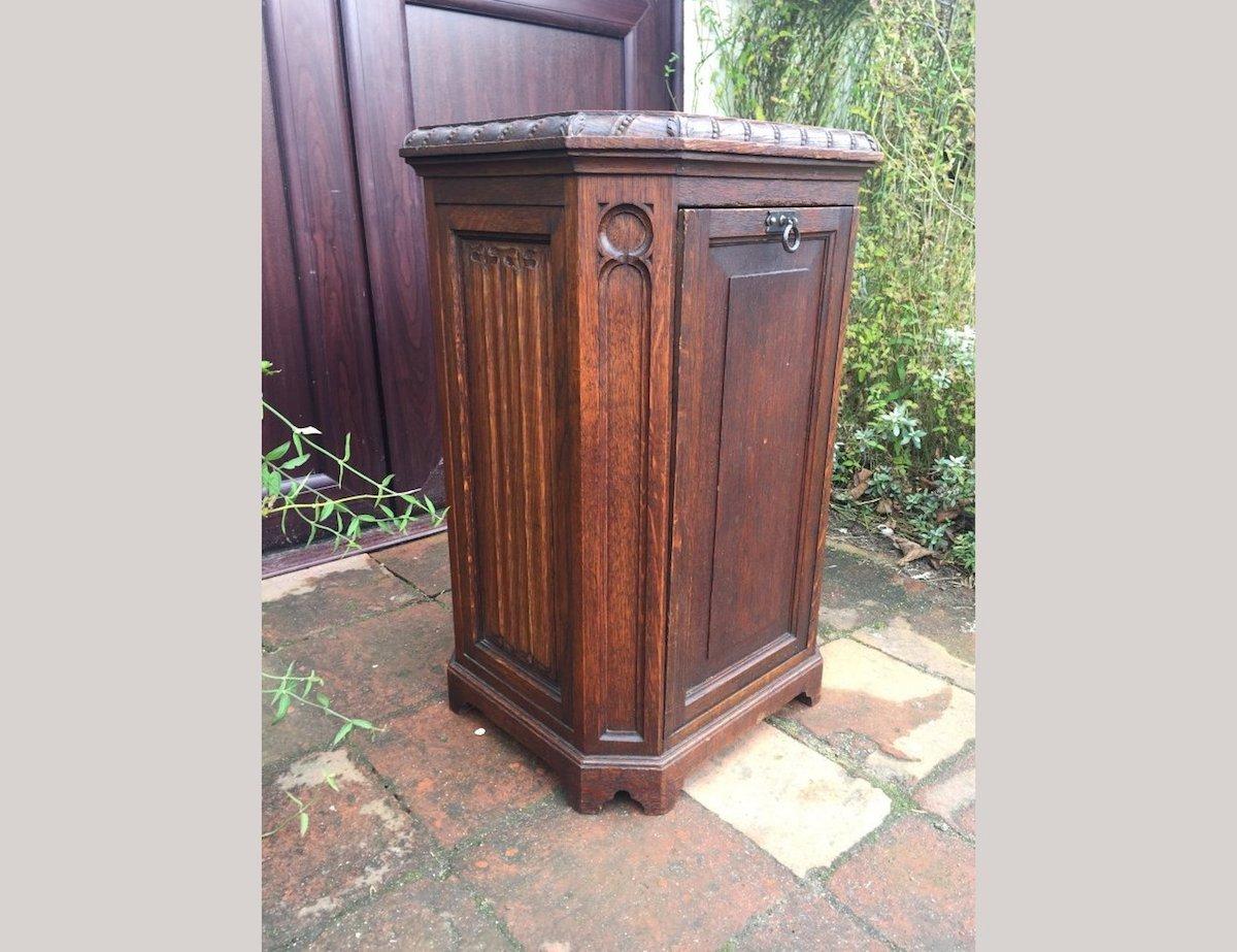 A.W.N Pugin style of a Gothic Revival oak coal purdonium with seed carving to the edge of the top and linen fold carvings to the front and to the sides with blind fret details to the canted edges.
  