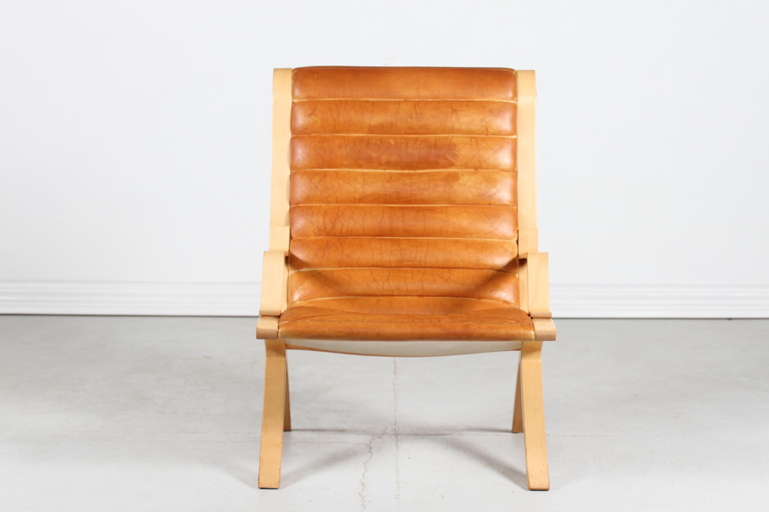 Vintage AX-chair by the Danish architects Peter Hvidt & Orla Mølgaard.

The chair is made of steam bend beech with lacquer and upholstered with cognac colored natural leather with great patina.

Manufactured by Fritz Hansen A/S in 1978

The