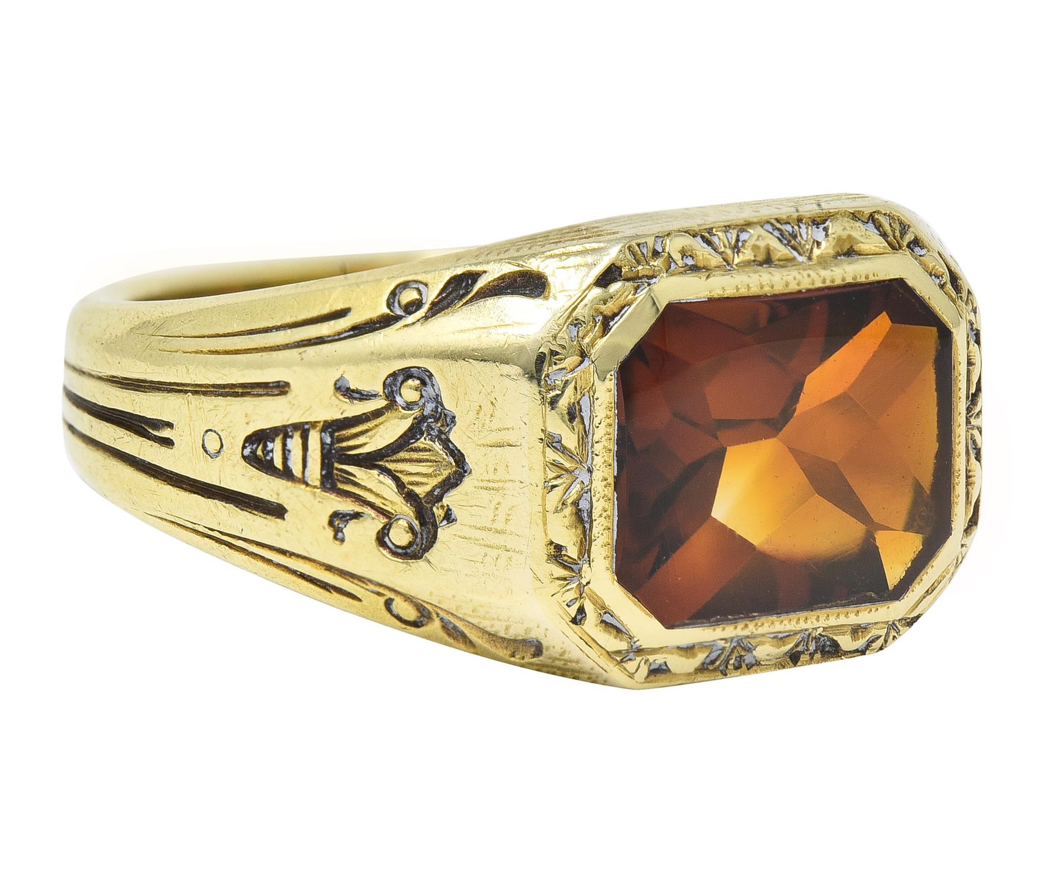 Centering an octagonal shaped mixed cut citrine measuring 7.0 x 9.5 mm 
Transparent medium brownish-orange in color - flush set
Featuring an engraved garland motif surround 
Flanked by engraved lotus motif shoulders 
With linear and scroll motif