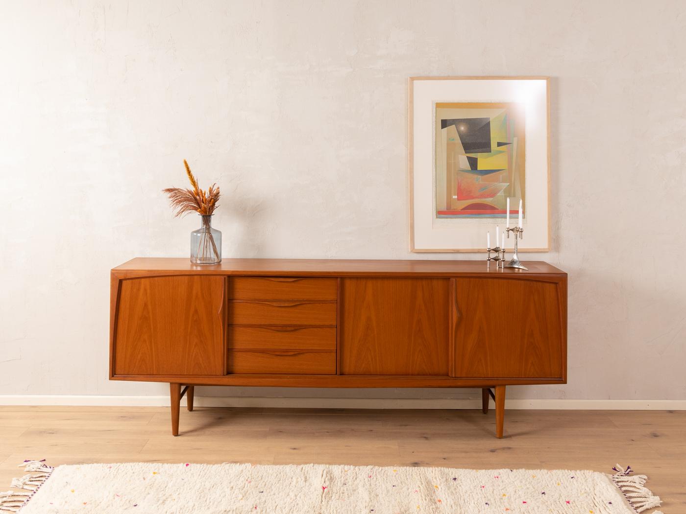 Classic sideboard from the 1960s. High-quality corpus in teak veneer with three sliding doors, four drawers, three shelves and cigar shaped feet.

Quality Features:
    accomplished design: perfect proportions and visible attention to detail
   