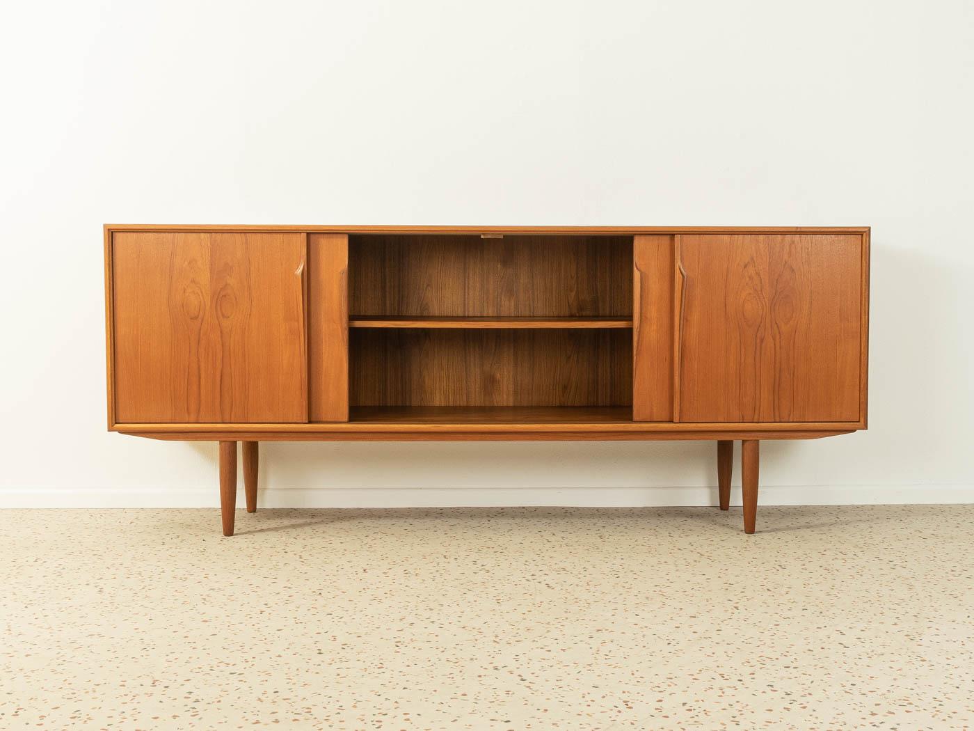 Classic sideboard from the 1960s by Axel Christensen for ACO Møbler. High-quality corpus in teak veneer with four sliding doors, two shelves, three internal drawers and cigar shaped feet.

Quality Features:
- accomplished design: perfect
