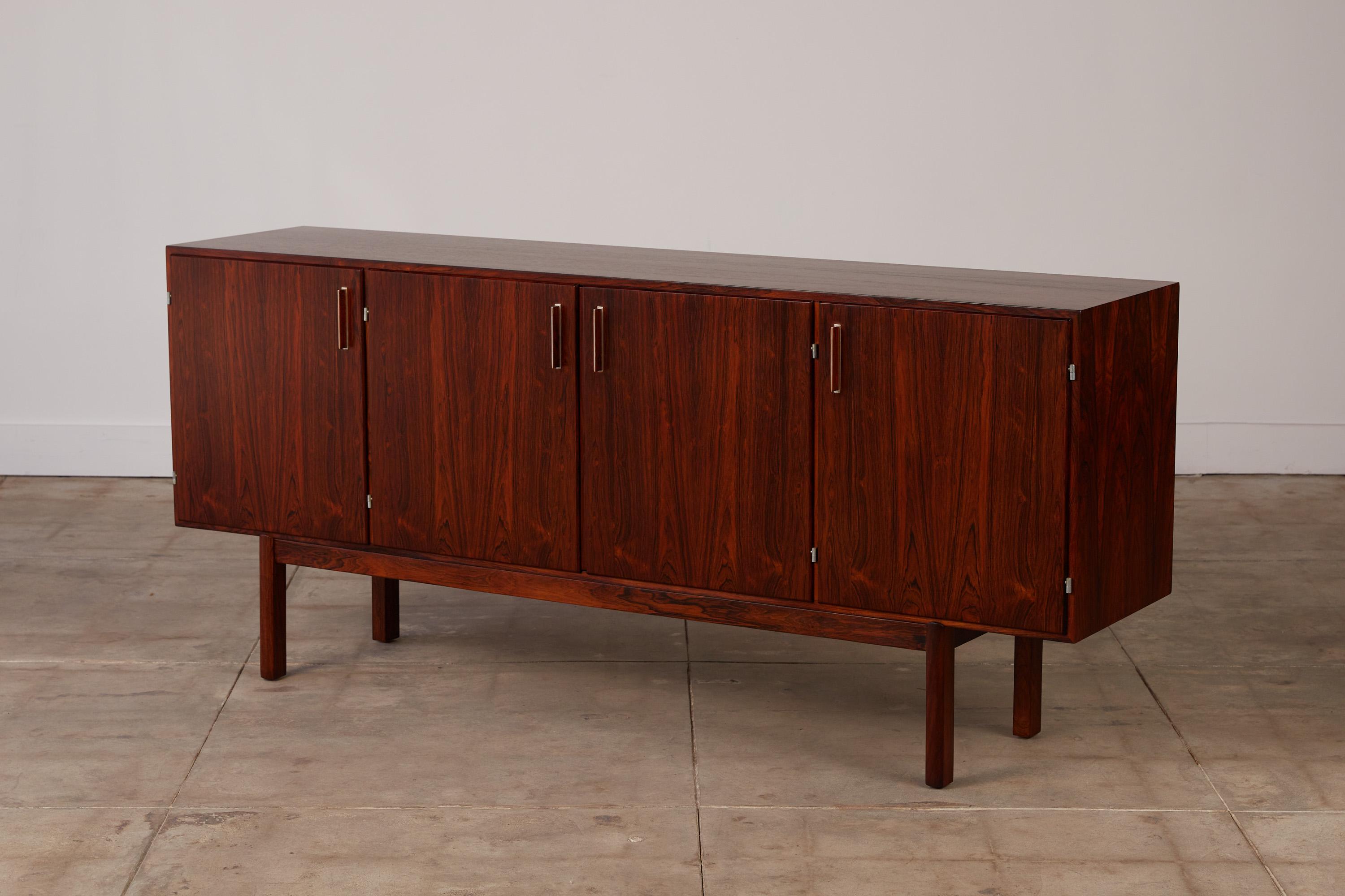 Danish modern rosewood credenza by Axel Christensen for ACO Mobler, Denmark, c.1950s This stunning rosewood credenza is equipped with three sections for storage - two of which have adjustable interior shelves and one features multiple drawers. It