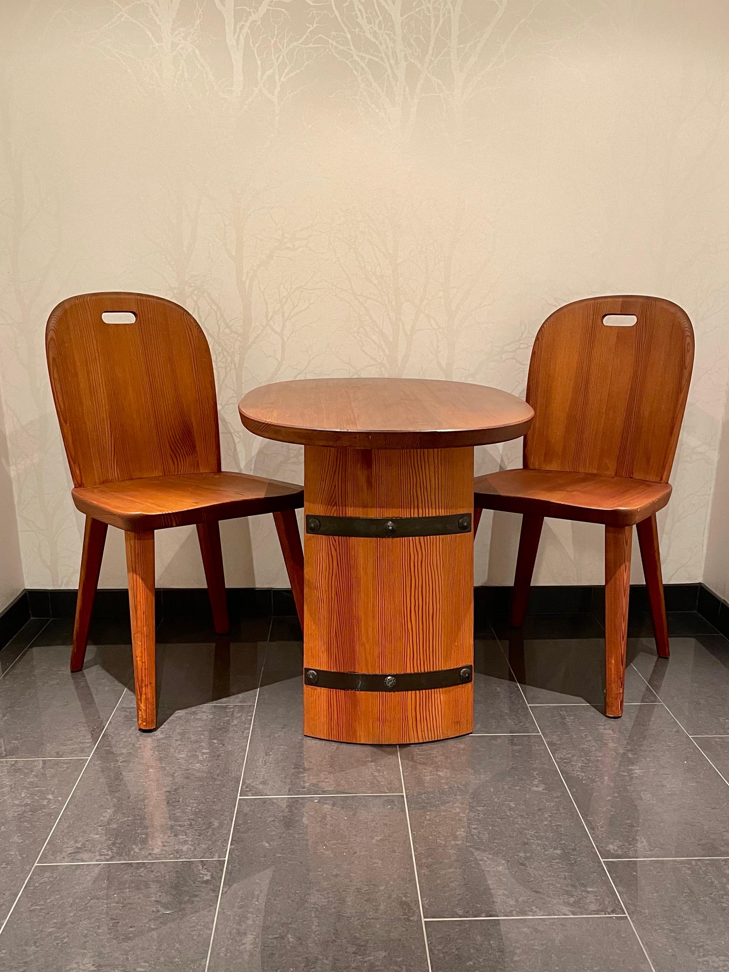 This is the Swedish pine coffee table set “Lövåsen” in Axel Einar Hjorth-style, manufactured by Åby Möbelfabrik in the 1930/40s. 

This stained solid pine set comes with a table and two chairs. 
The table has a 3.5 centimeter thick, oval shaped top