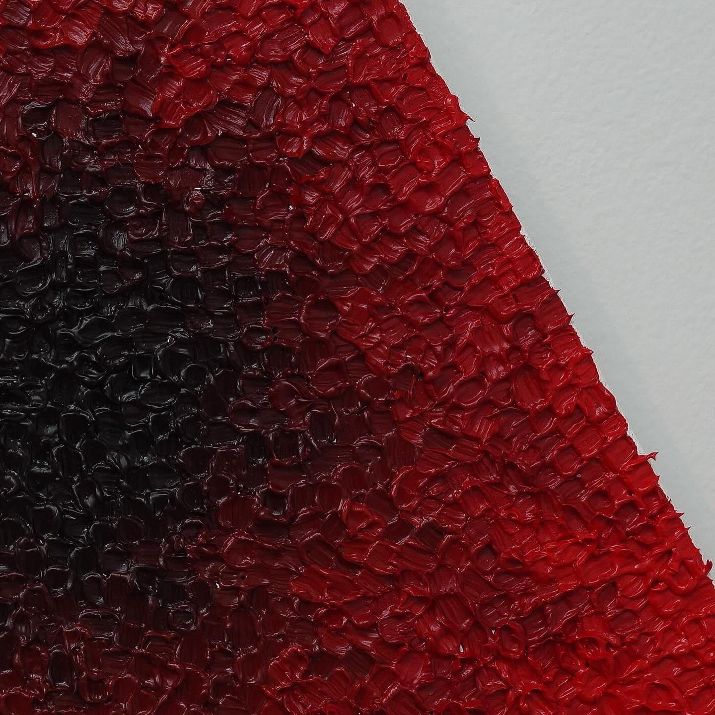 Titled 'Carnal,' this triangular work leverages abstraction to delve into complex and deeply unsettling territory. The artist utilizes a dense, agitated impasto surface that moves from a dominant, saturated cardinal red at the periphery to a