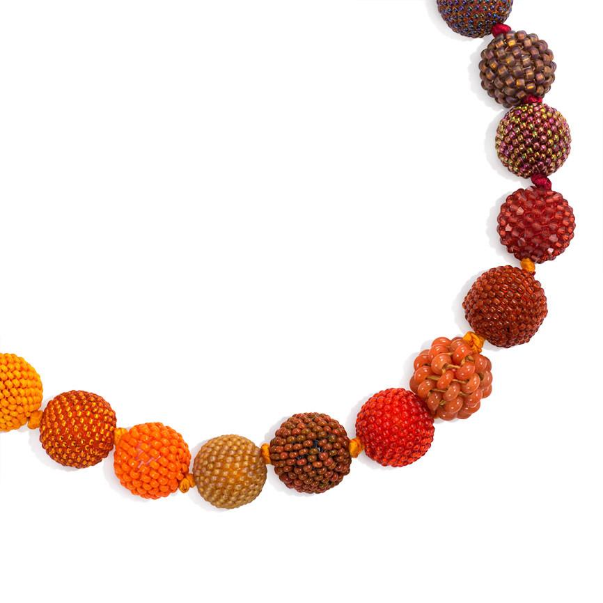 A long hand beaded ball necklace comprising 43 glass, crystal, and plastic beaded spheres in red, orange, purple, and brown tones.  Axel Russmeyer, Germany.  Approximately 34