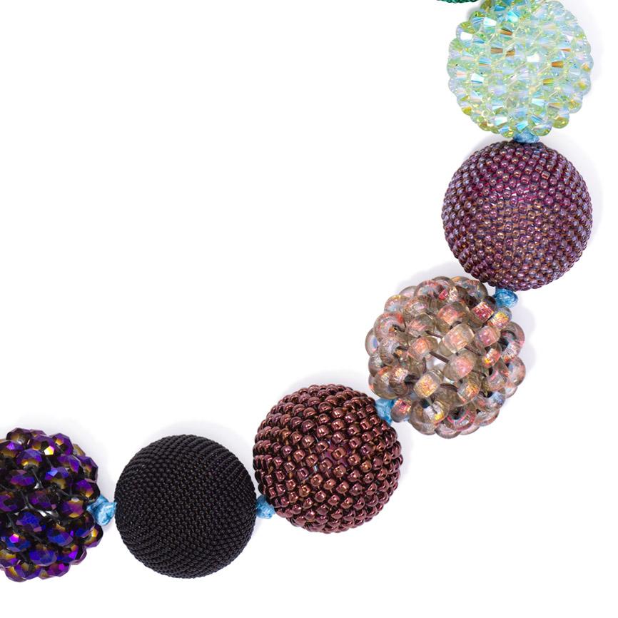 Collier boule à 16 perles fait main dans le style Wiener Werkstätte, composé de perles de verre et de cristal de tailles et de textures variées dans des tons verts, prune lustrée, bronze et violet, complété par une fermeture à baïonnette en or 18