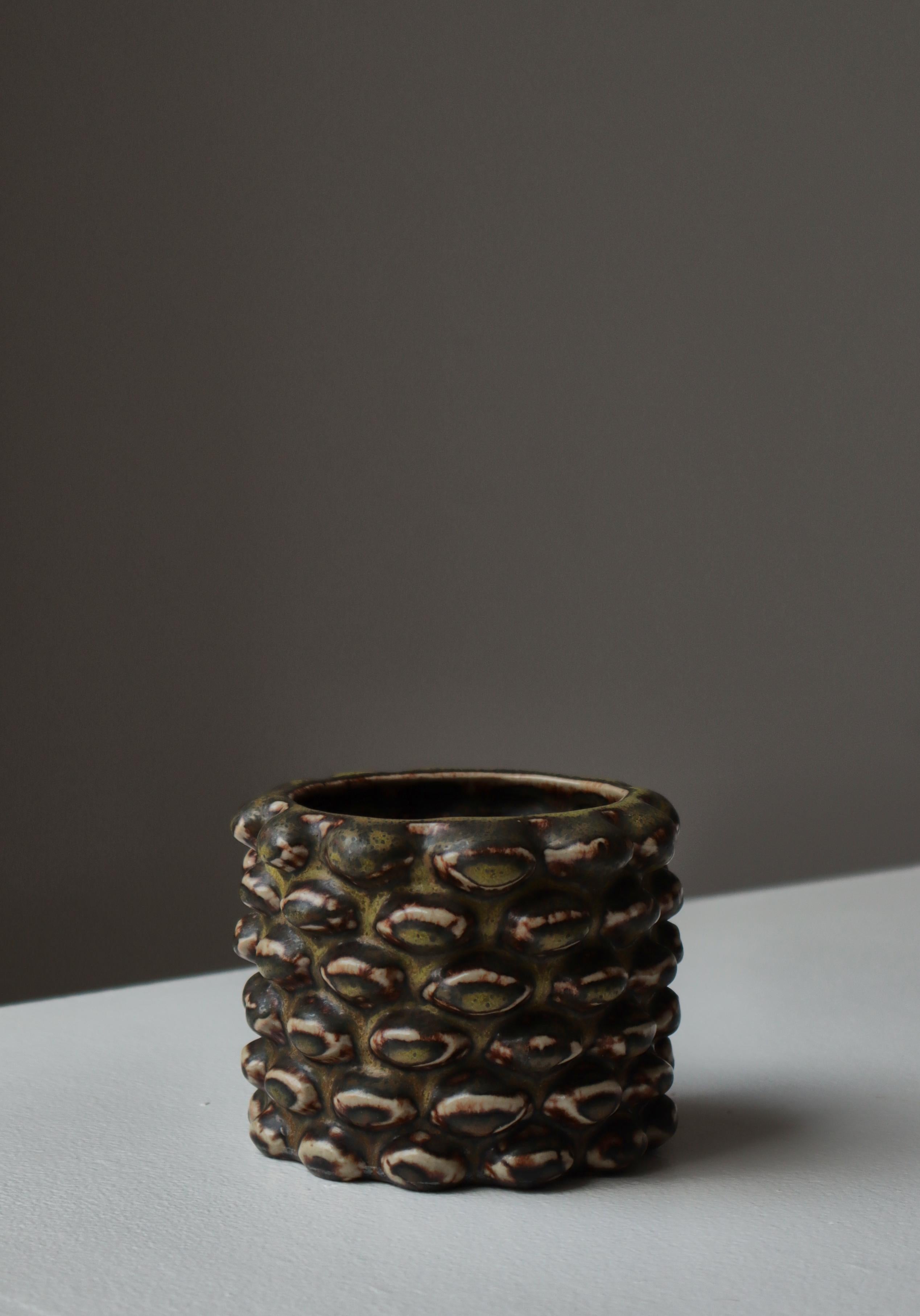 Una tazza in gres riccamente strutturata di Axel Salto, modello 20702, realizzata da Royal Copenhagen e rifinita con il celebre smalto Solfatara di Salto. Questa forma scultorea, caratterizzata da sporgenze dense e simili a semi, appartiene