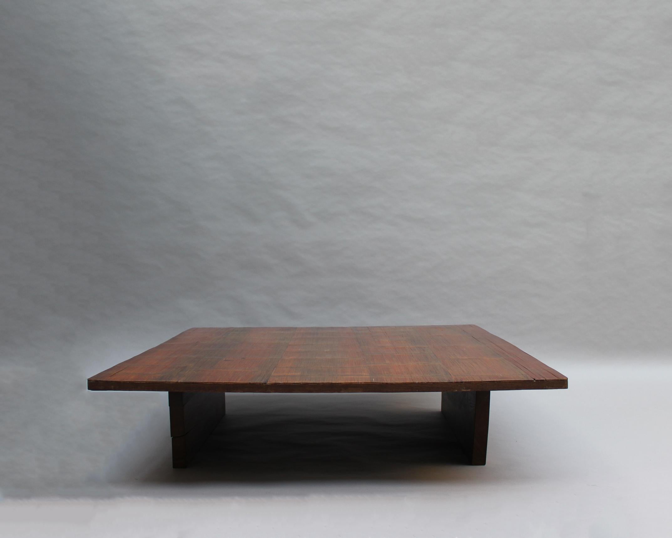 A large low square table with a bamboo top on a solid wenge wood base.
This table was part of a décor by Axel Vervoordt, as shown on his book, page 25, edited by Assouline.


