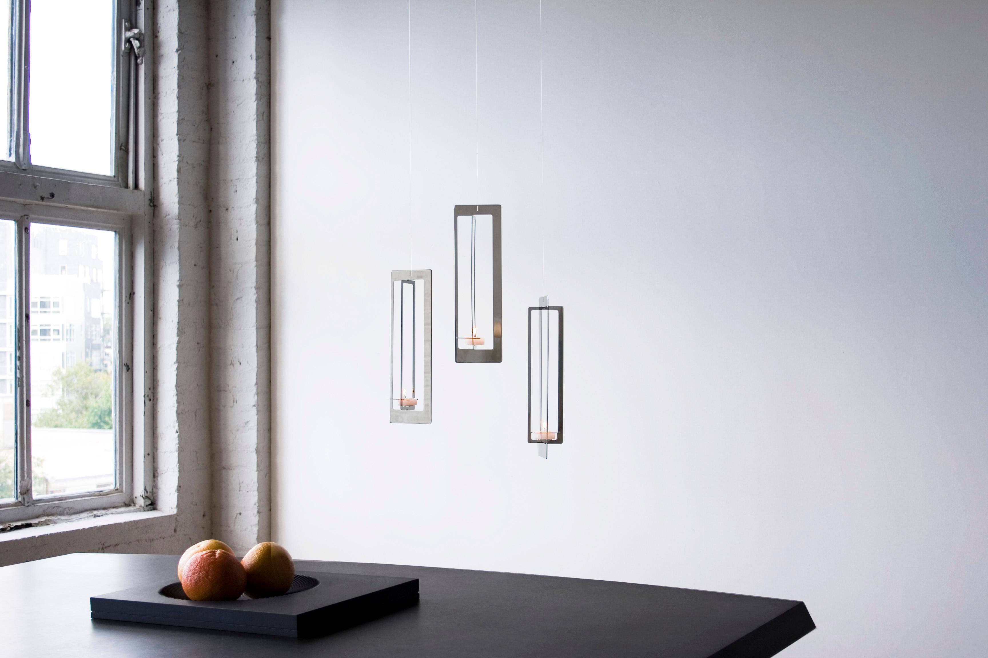 With attention to every edge and surface, we crafted a brushed stainless steel hanging candle holder with depth and vibrancy that reflects a candle’s glow in strips and slivers. Conceived as the contemporary charms of a design-it-yourself