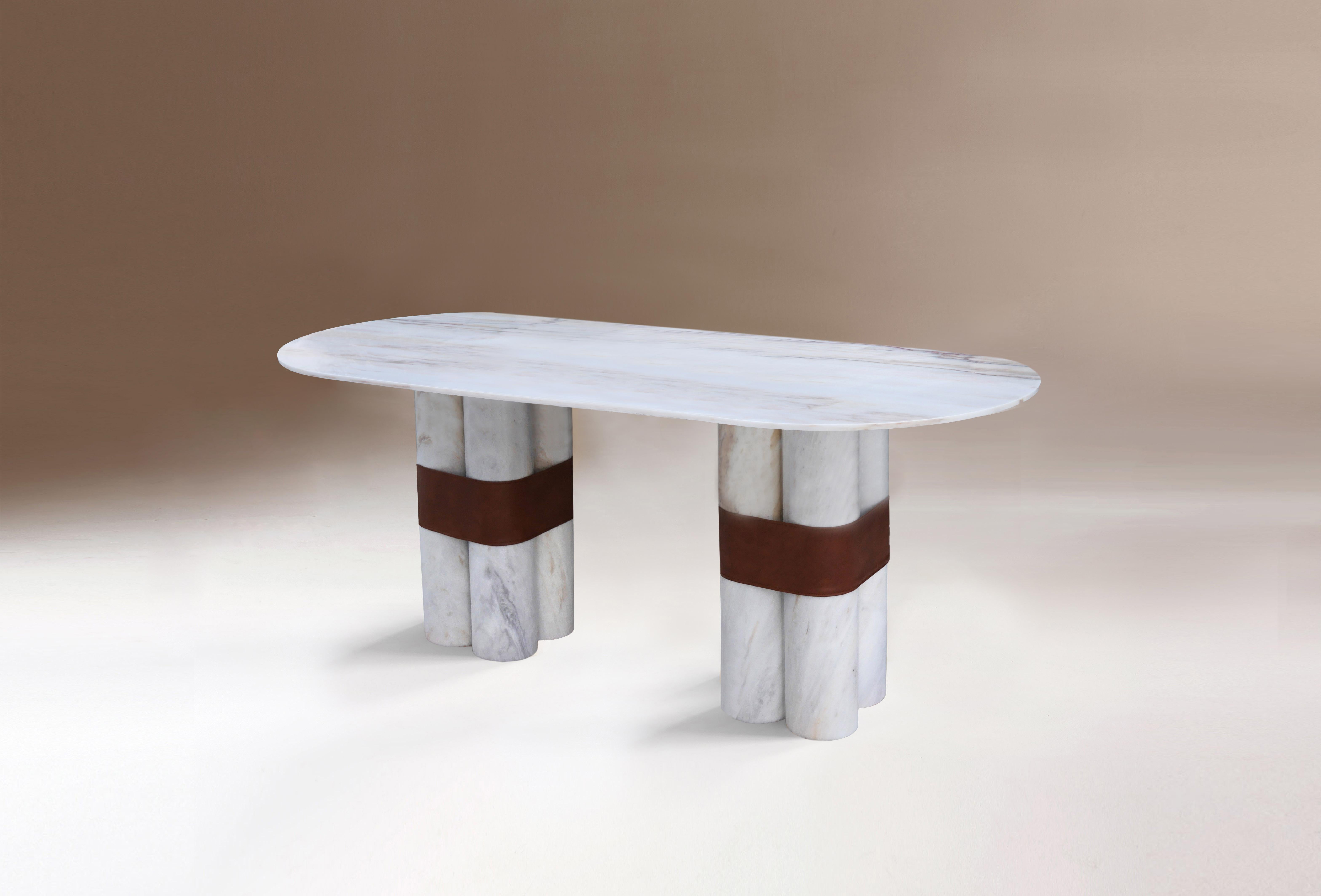 Axis is a full marble table. Its base formed by two thin blocks resembling round columns and its round top create an almost architectural balance. It also has a final and unexpected touch thanks to the handmade eco leather belt that embrace the