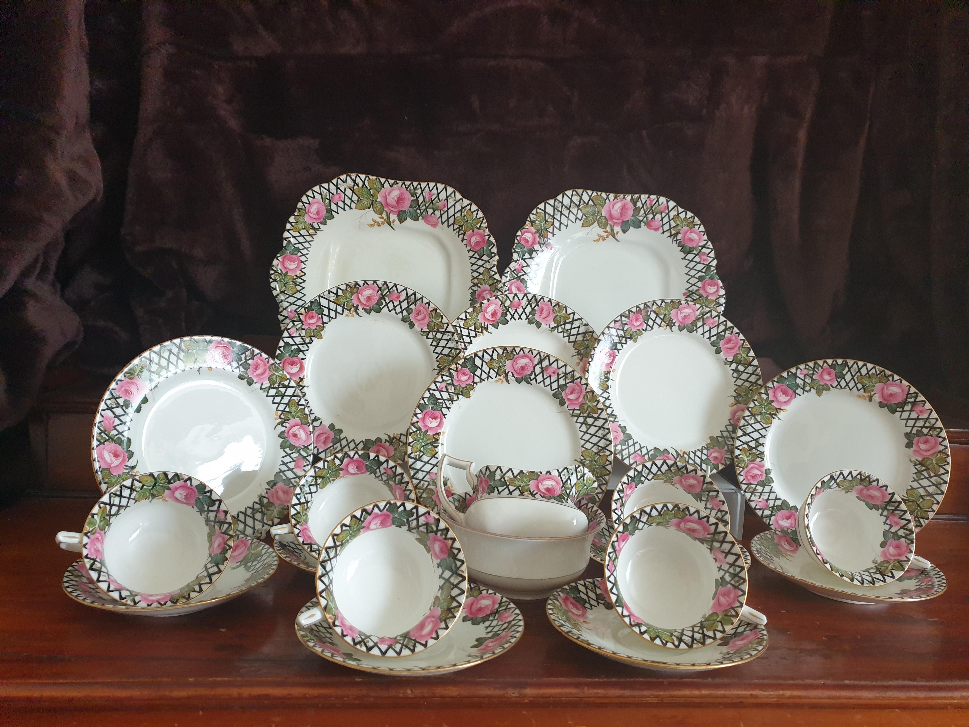 An early 20th century Aynsley Art Deco Roses tea service comprising of 6 cups, 6 saucers, 6 cake plates, sugar bowl, creamer and 2 large cakeplates. The Tea Service is decorated with handpainted pink roses set behind a fence. 
Makers stamp to the