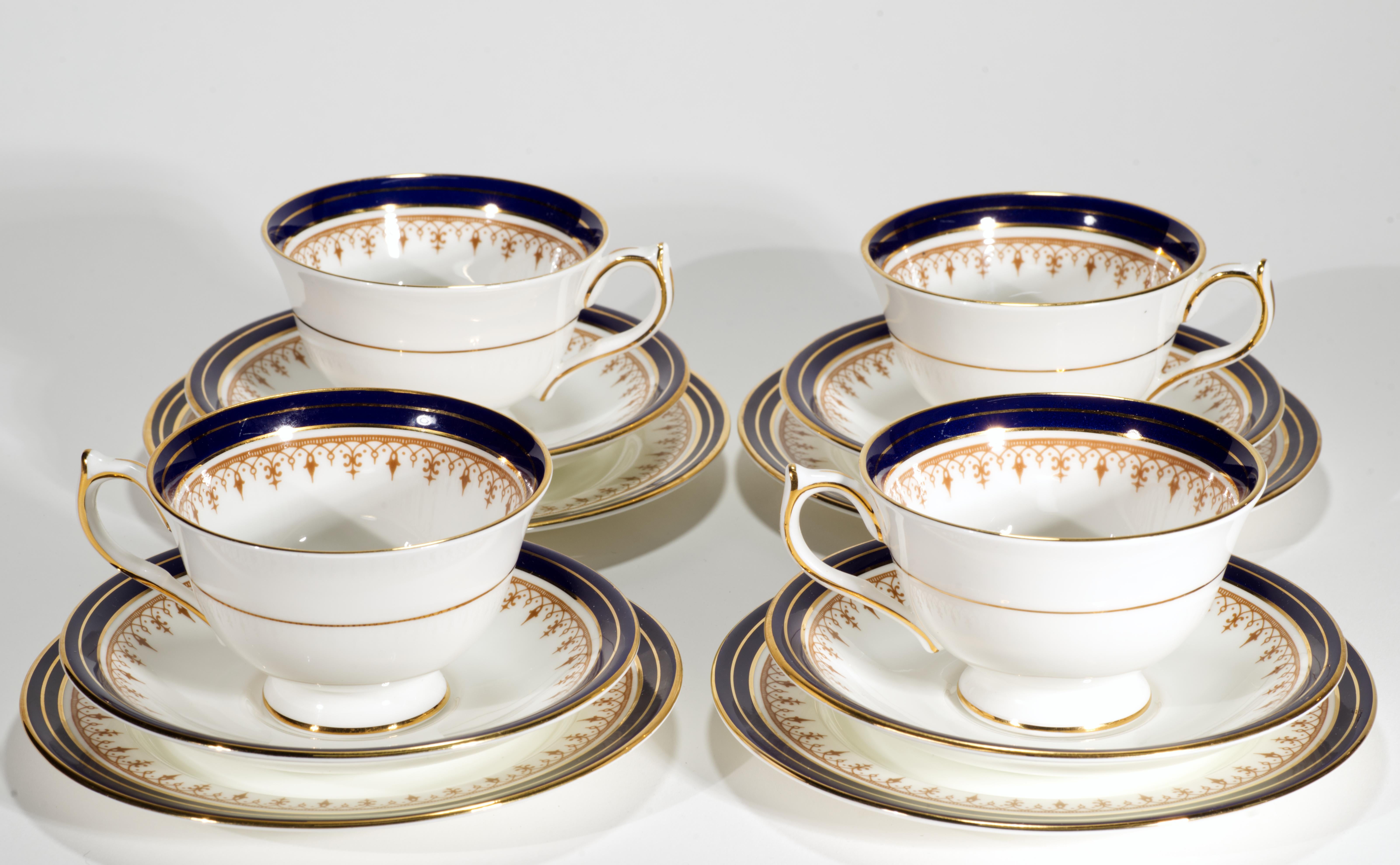  Il set vintage di 4 tazze, 4 piattini e 4 piatti da pane o da dessert è decorato con il motivo Leighton in colore Cobalto. Le tazze con piede hanno un decoro a fascia dorata all'esterno della tazza e sui manici, e un'elaborata fascia blu cobalto e