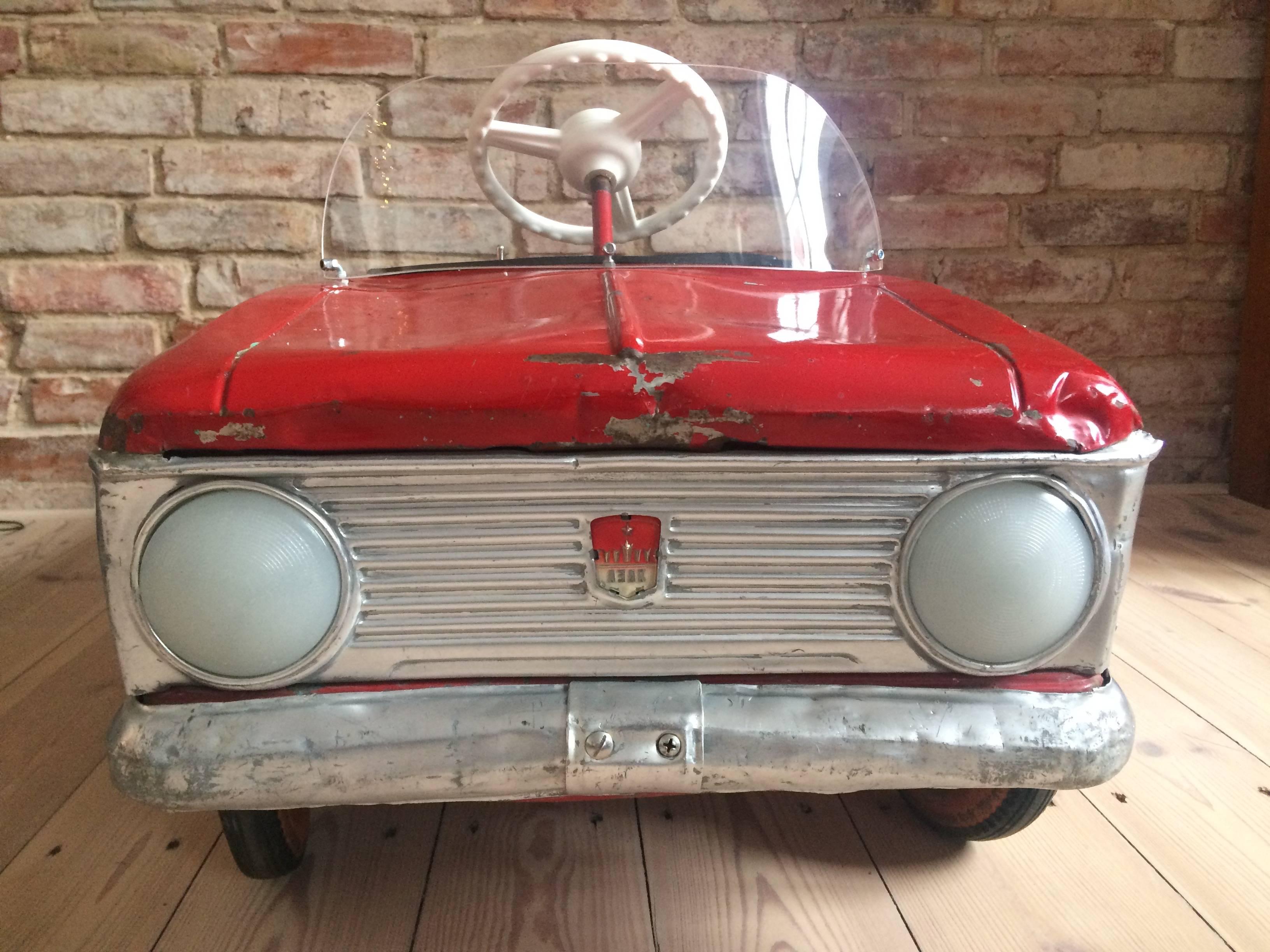 This early Soviet child's pedal car was manufactured during the communist era in former Czechoslovakia. It was created as a model for children as a small copy of the original Moskvich car and works on a pedal moving system. The piece features fully