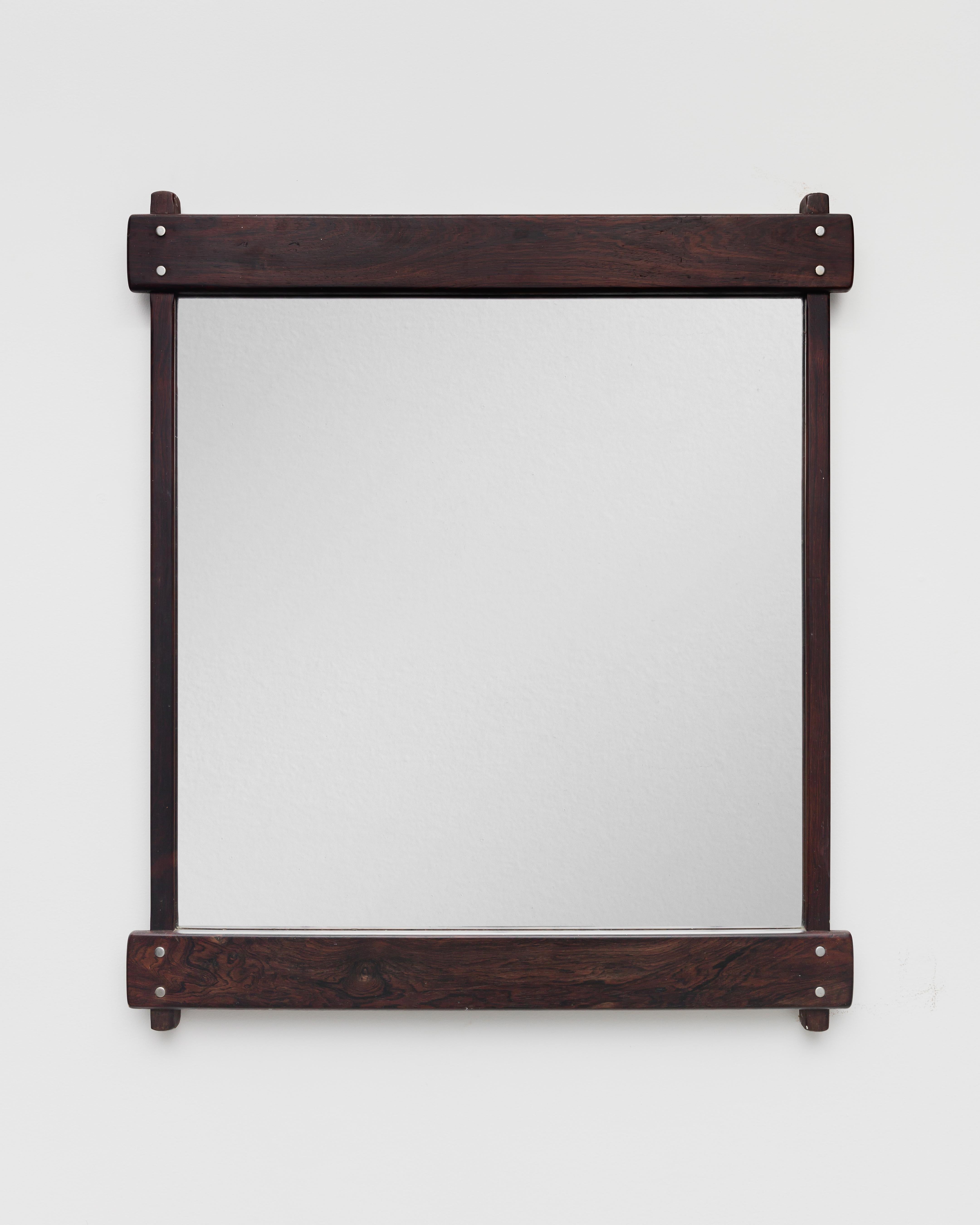 The Azen Mirror is made with a Rosewood frame and has brass details. This piece was designed by Sergio Rodrigues and manufactured by Oca in 1965. 