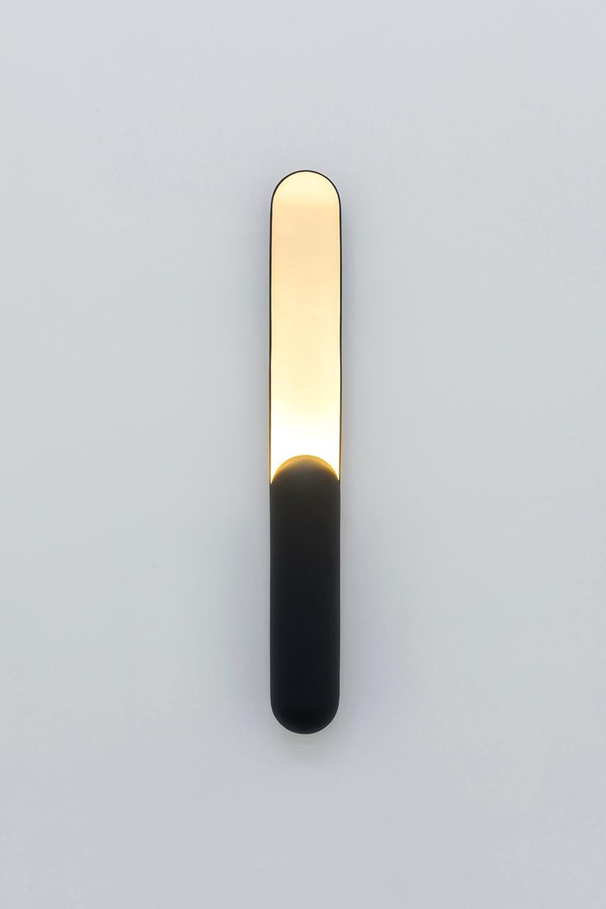 Azo est né de l'intention de créer une applique avec un éclairage vertical.
Sa forme est le résultat d'une coupe longitudinale dans un cylindre aux extrémités arrondies,
dont la longueur est réduite d'un côté pour abriter la source lumineuse.