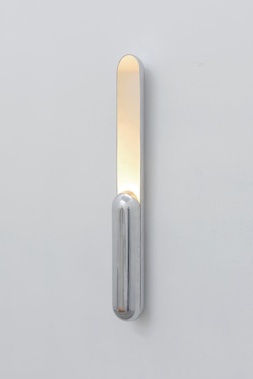 Azo comes from the intention of creating a sconce with vertical lighting.
Its shape is the result of a longitudinal cut in a cylinder with rounded ends,
with the length reduced on one side to shelter the light source. 
The lighting, in turn, is