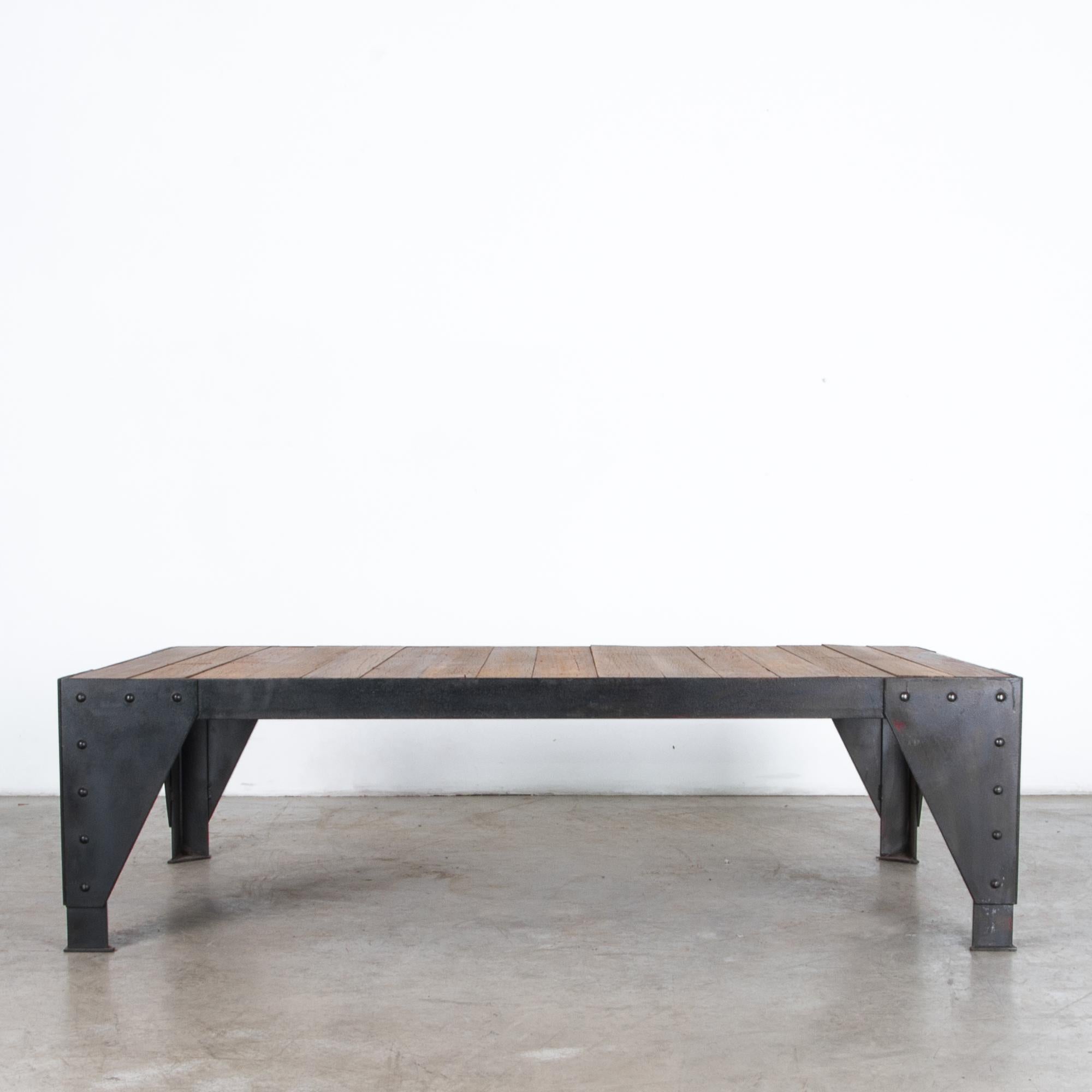 A sturdy iron base supports durable azobe, a tropical hardwood, in this chic coffee table. Influenced by modern forms, and the rustic simplicity of industrial construction techniques. Angle braces become bold geometric legs, rivets create a