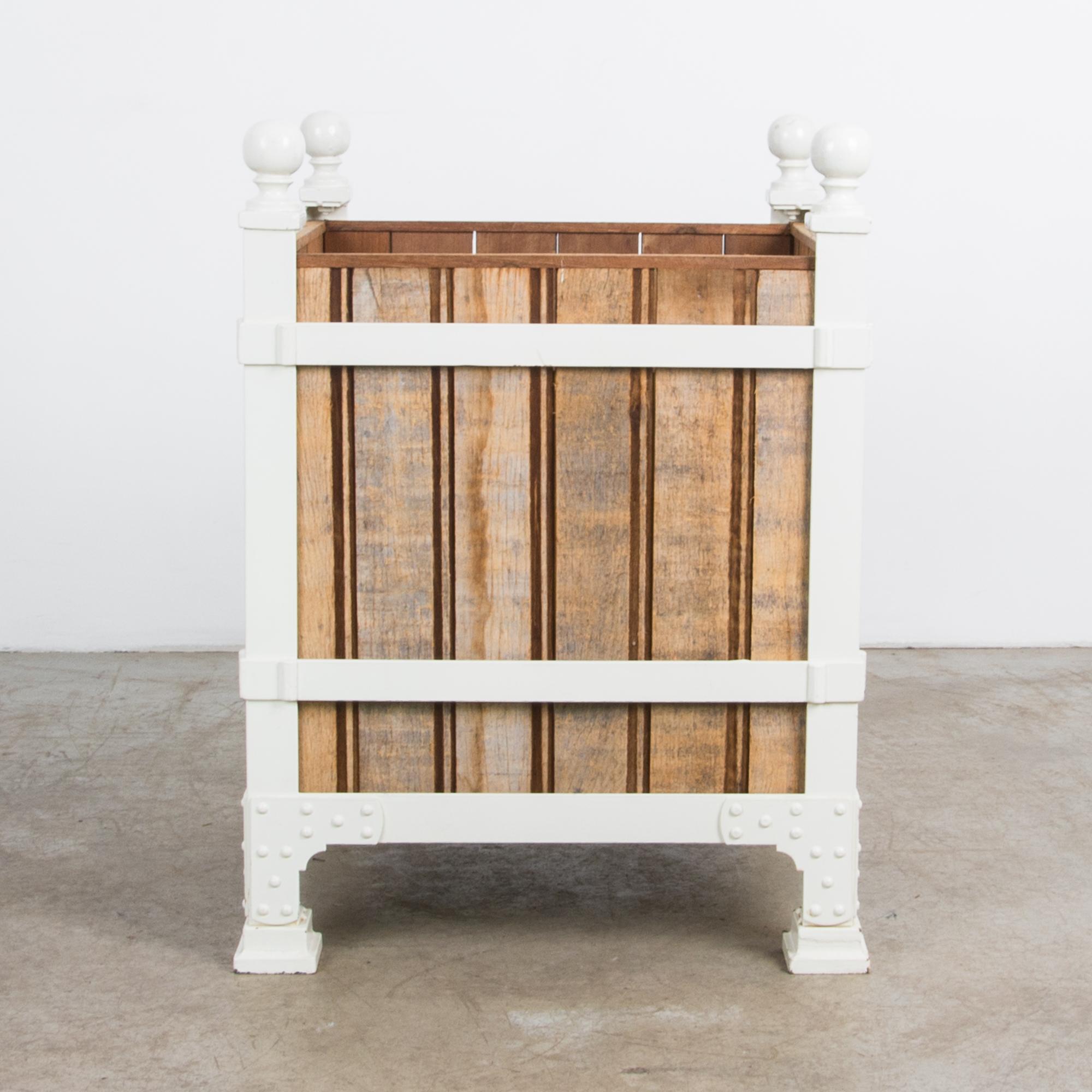 Une robuste jardinière en bois fabriquée dans notre atelier. La finition chaude met en valeur le bois brut d'adobe qui contraste avec le cadre métallique peint en blanc. La solide construction en fer devient un motif décoratif, avec des rails