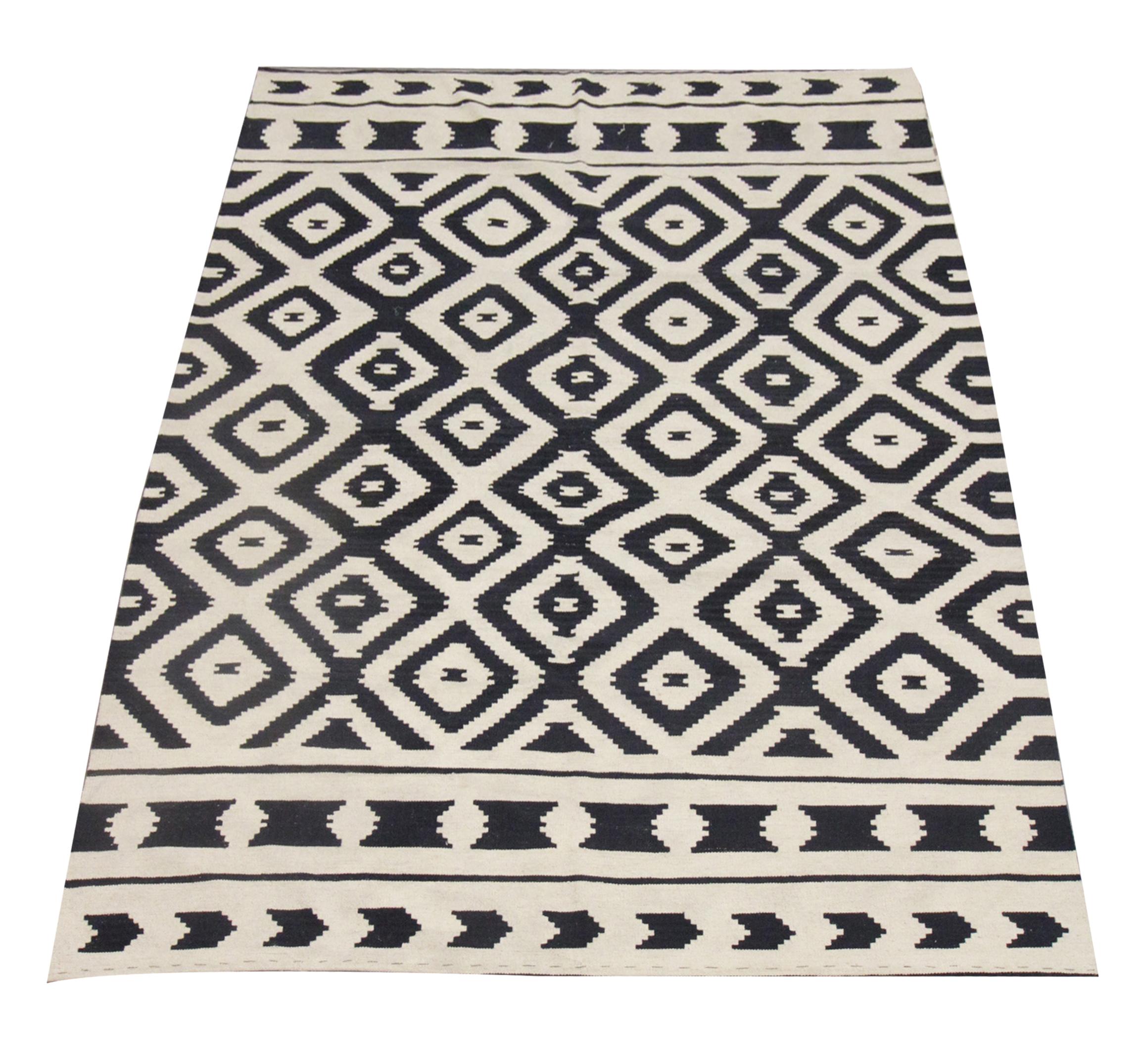 This modern wool rug is a handwoven Kilim constructed in Afghanistan in the early 2000s. The design has been woven with a simple Aztec, contrasting colour palette featuring black and cream. The design features a repeating geometric pattern with