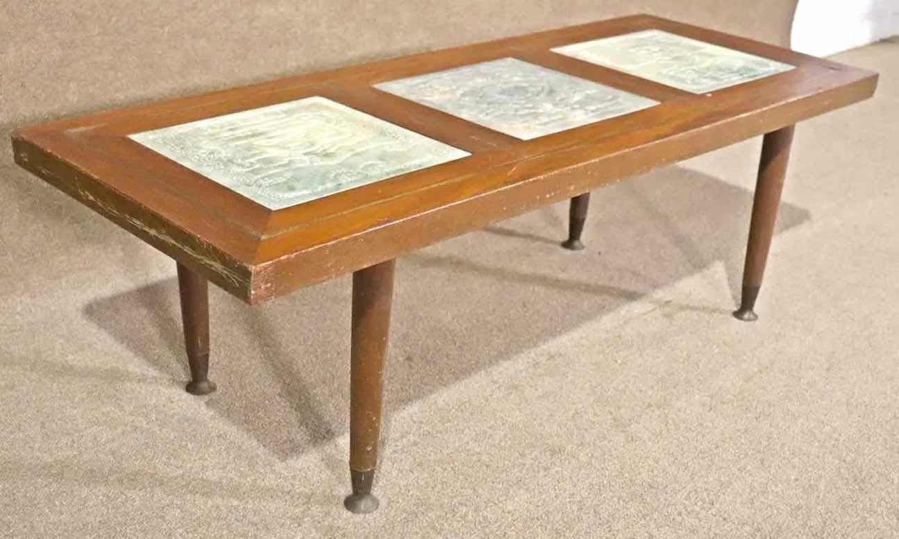 Mid-century long coffee table with carved alabaster plaque inserts. Beautifully sculpted Aztec style motifs set in a modern table with accenting brass inlay.
Please confirm location. 
 