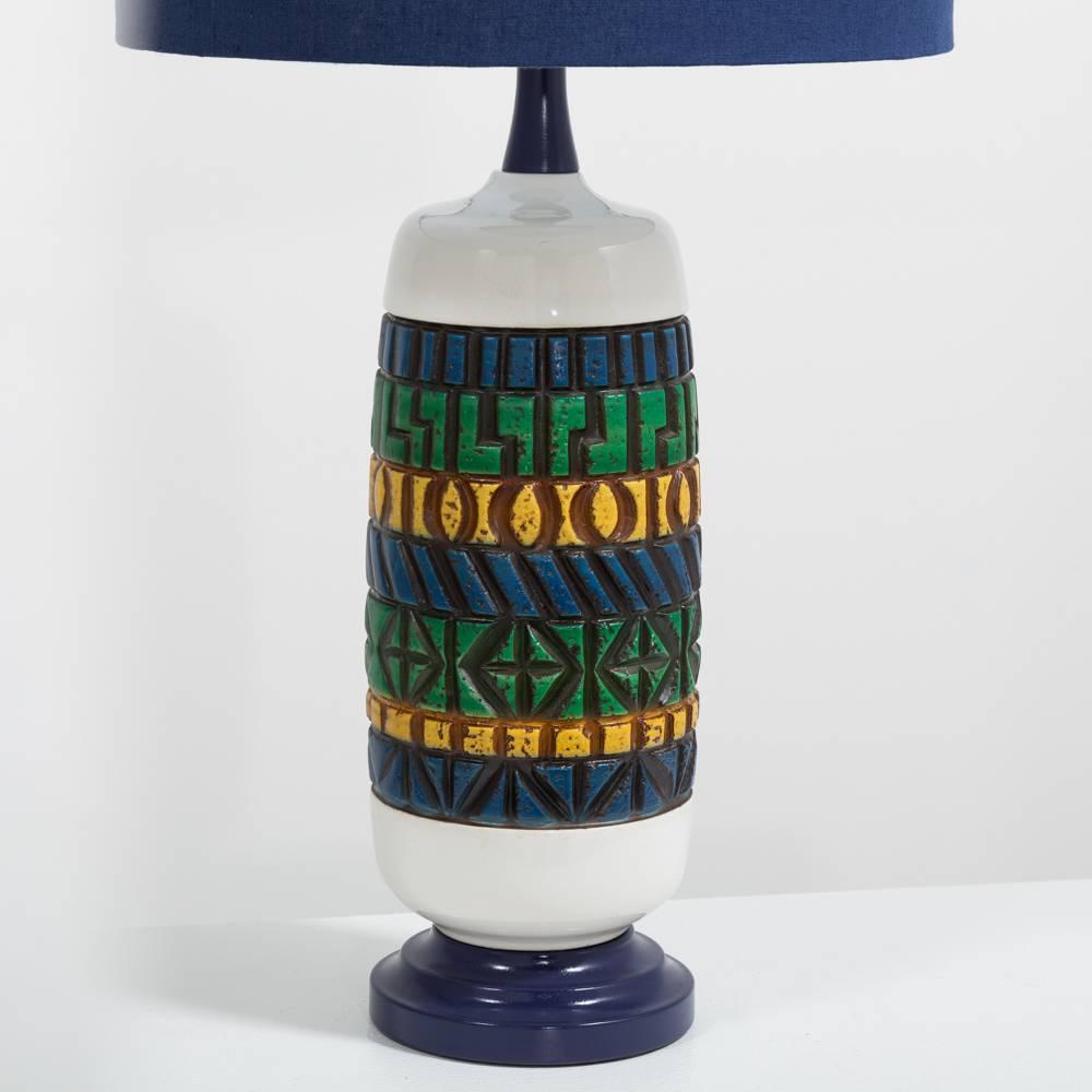 Aztec style single ceramic lamp with moulded bands of yellow, green and blue on a wooden base and finished with a navy blue linen shade, 1970s.
Measurements are for the base.
