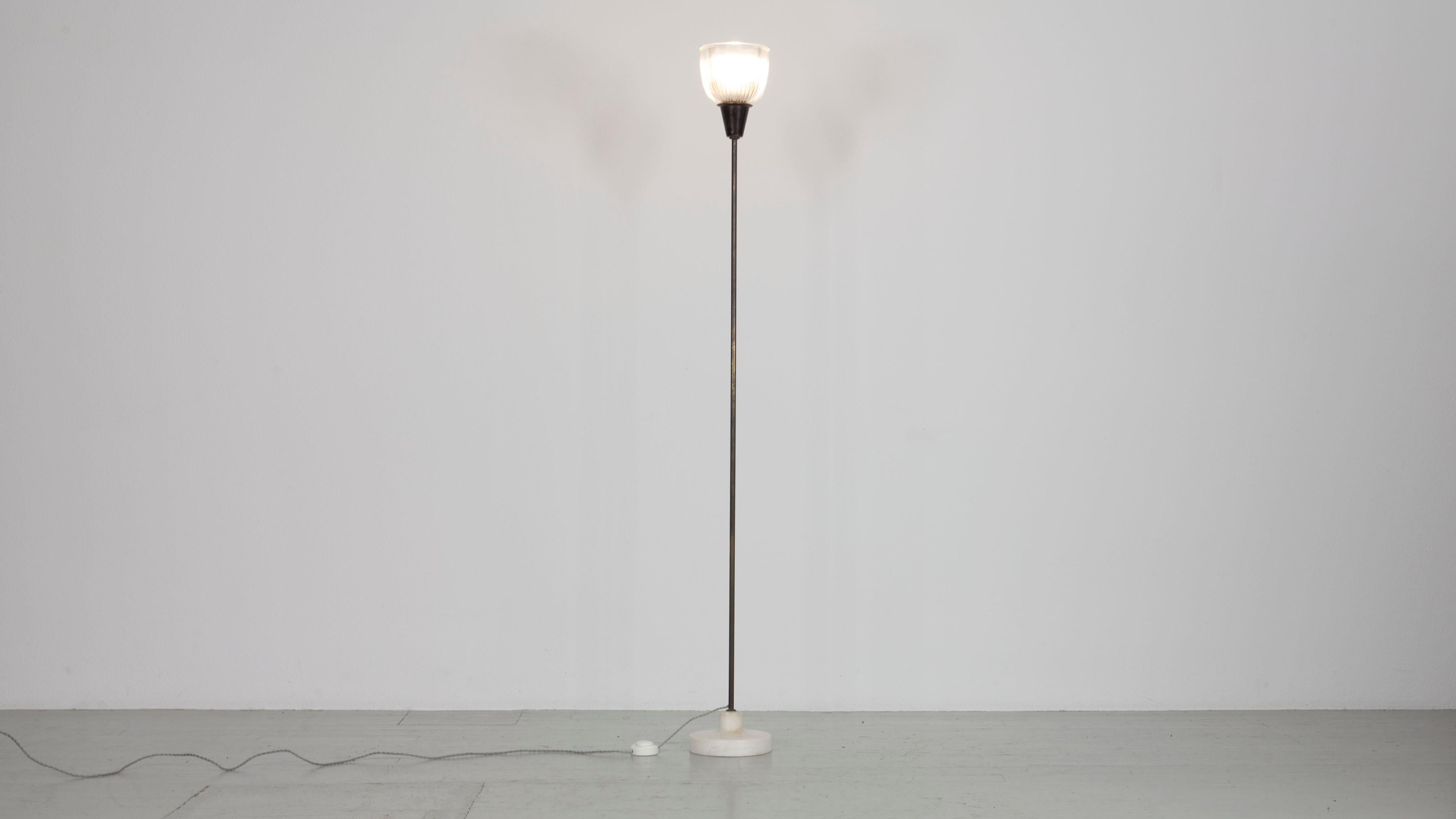 This Italian floor lamp from 1954 was designed by Ignazio Gardella and manufactured by Azucena. It is the model LTE 6 and consists of a brass frame on a marble base and a ribbed glass lampshade. It has an E27 socket and is in good condition except