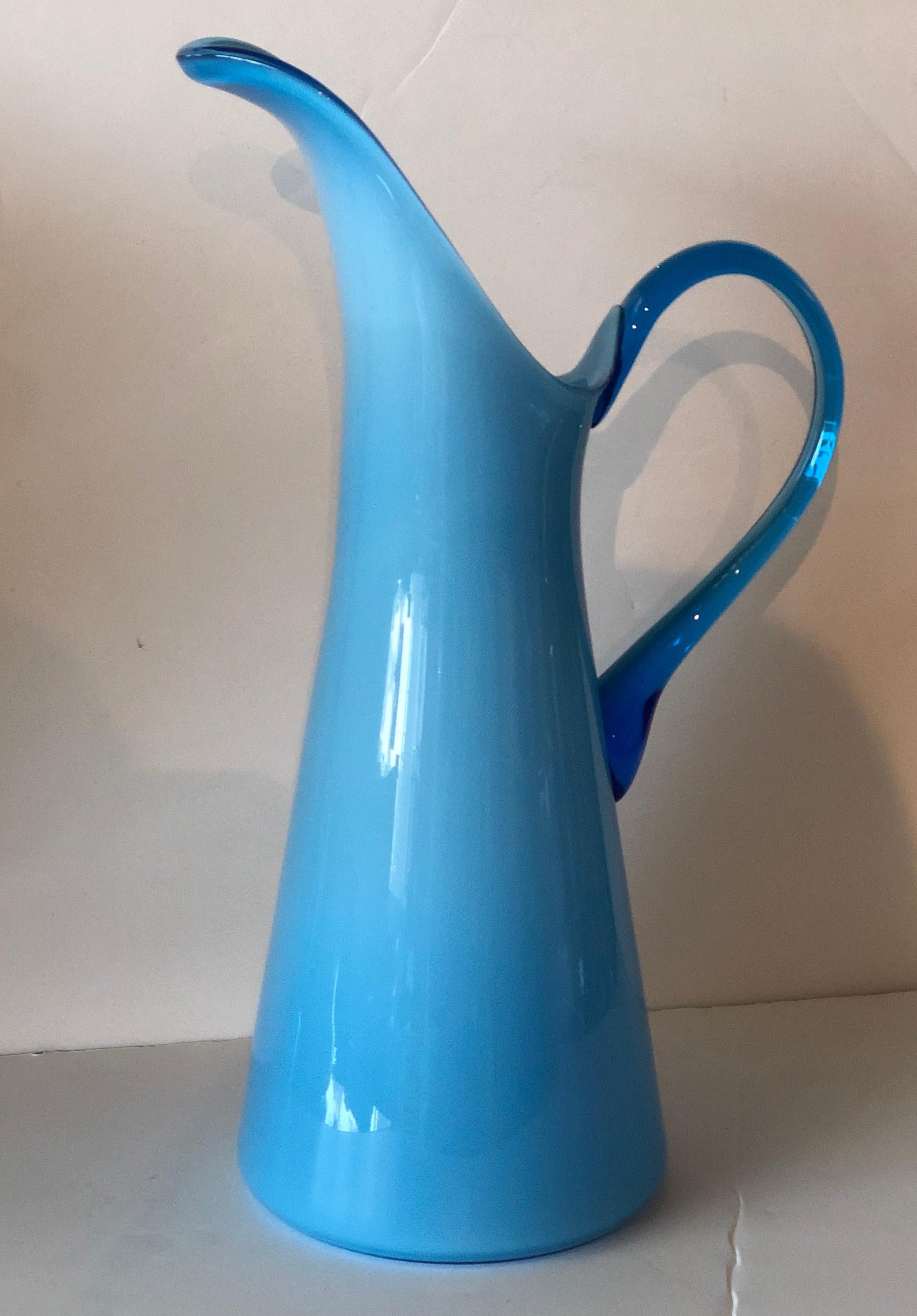 Offered is a Mid-Century Modern Italian Azure blue over white cased glass pitcher with translucent darker blue handle. This lovely shade of Azure blue Venetian glass pitcher would make a lovely gift for the holidays or any occasion. We suggest