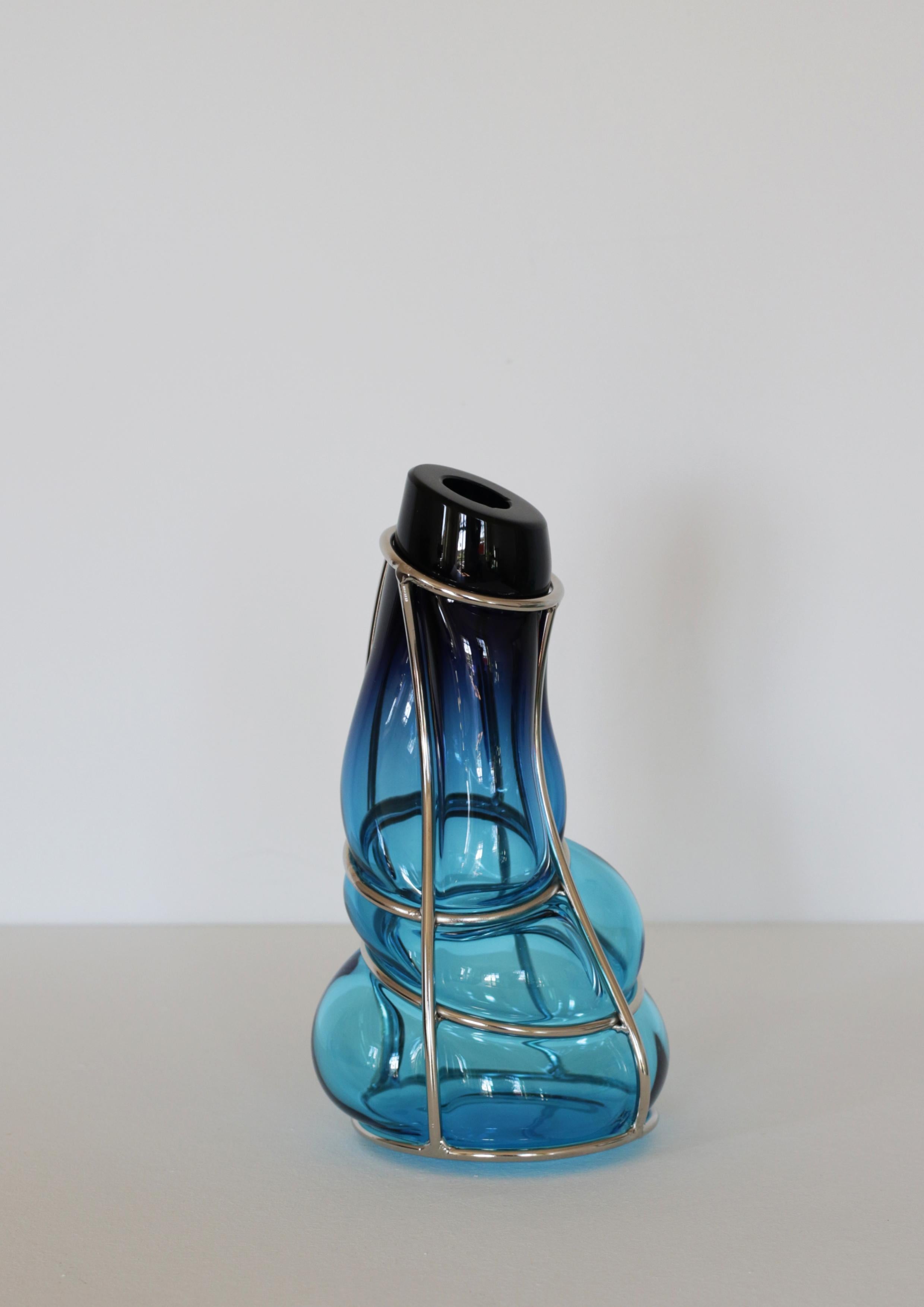 Vaso scultoreo Babà di Alice Crepaldi con sfumature azzurre e ametista
Un pezzo unico.
Dimensioni: D 16 x L 16 x H 30 cm.
Materiali: Vetro di Murano e metallo.

La collezione di vasi Babà esplora le complessità della lavorazione del vetro di Murano,