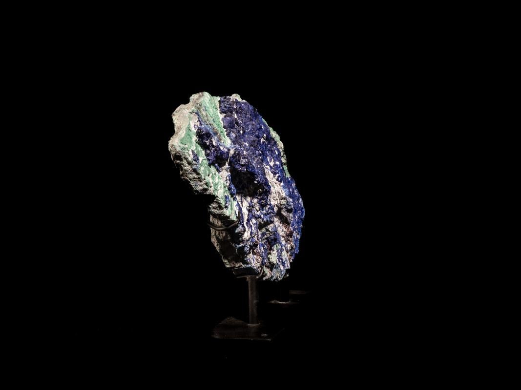 Azurite is a copper carbonate, usually found in combination with other copper minerals such as its much better known green brother malachite. 
The mineral is full blue in color and is virtually opaque with a silky sheen.
Azurite usually forms in