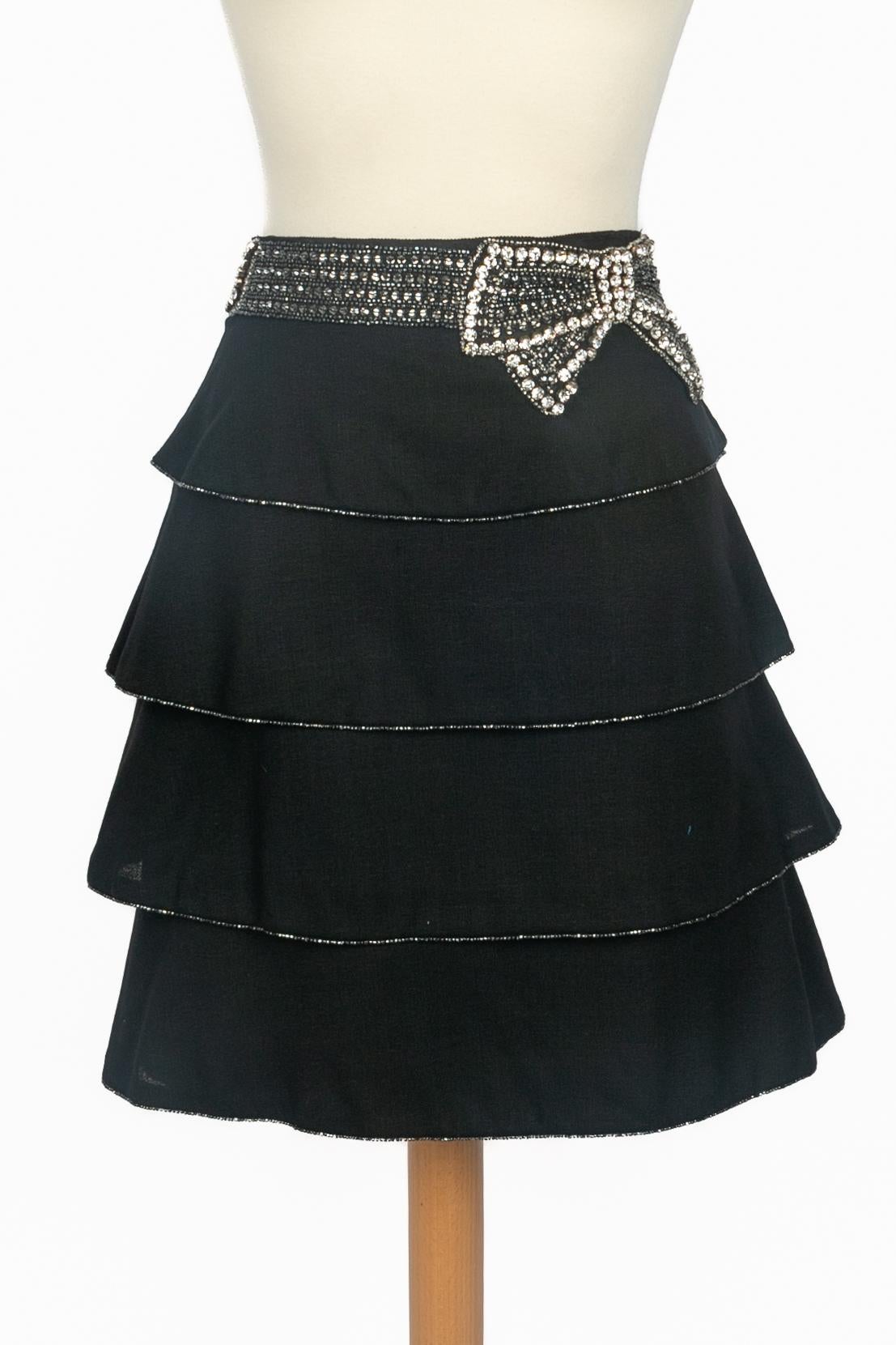 AZZARO - (Made in France) Jupe courte noire à volants décorée de strass et de paillettes. Taille 38FR indiquée.

Condit :
Très bon état.

Dimensions :
Taille : 41 cm - Longueur : 48 cm

SKU:FJ229