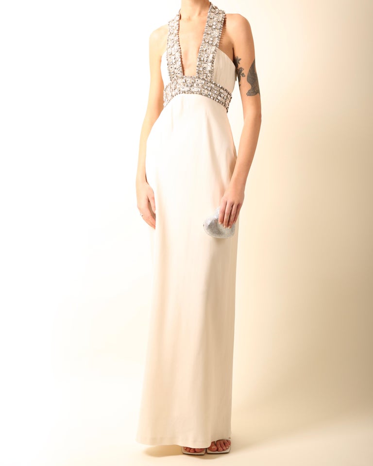 Azzaro
A beautifully elegant column style gown in ivory with a fully silver crystal and beaded embellished neckline, empire waist and halter strap
Low cut plunging neckline
Boning to the bust
Inner rubber lining to the bust keeps the dress perfectly