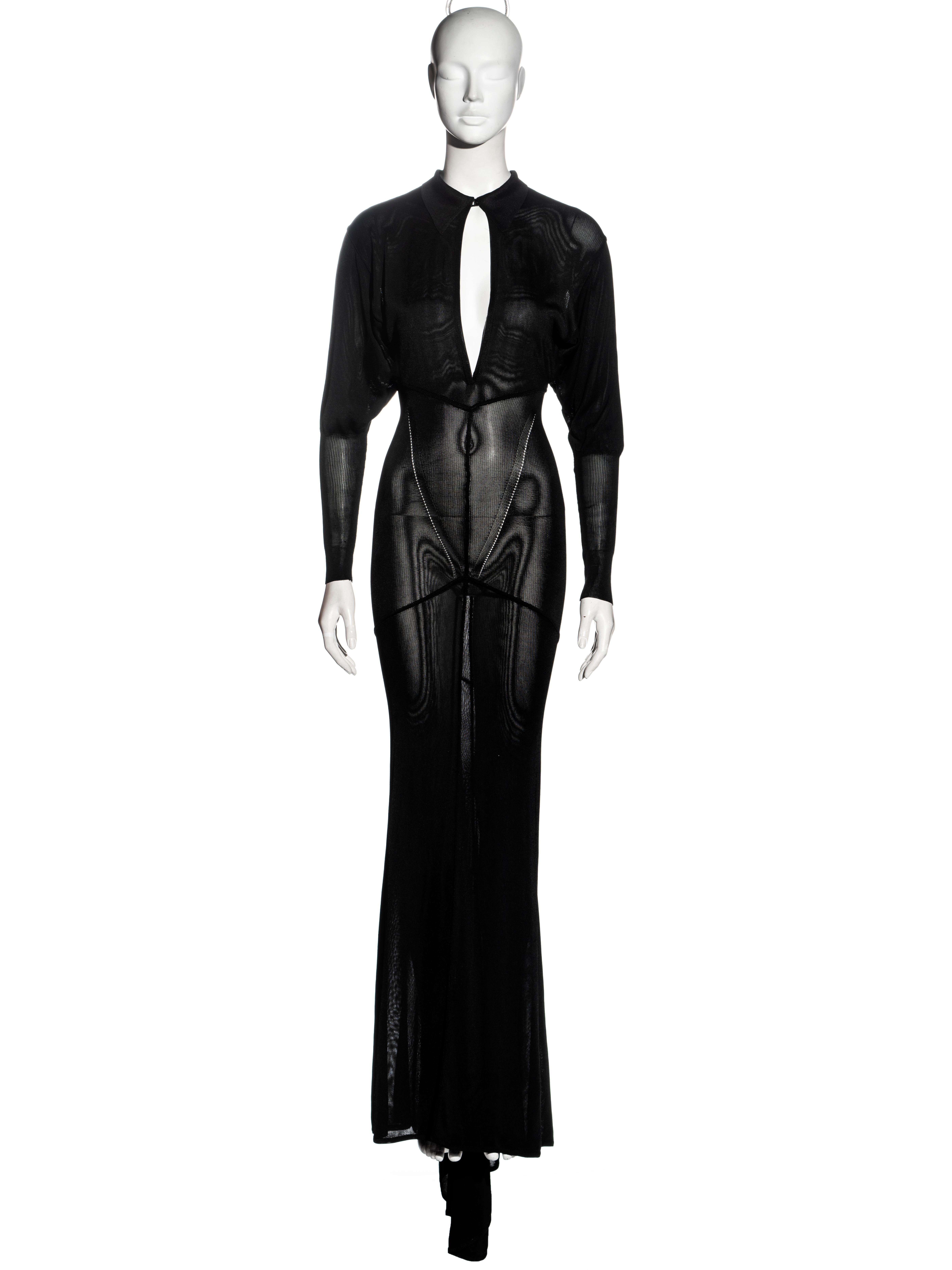 ▪ Azzedine Alaia evening dress
▪ Black acetate knit 
▪ Button-up collar with low-cut neckline 
▪ Leg of mutton sleeves
▪ Open-knit detail on the hips 
▪ Floor-length skirt with train 
▪ Size Small
▪ Fall-Winter 1986
▪ 100% Acetate
▪ Made in Italy