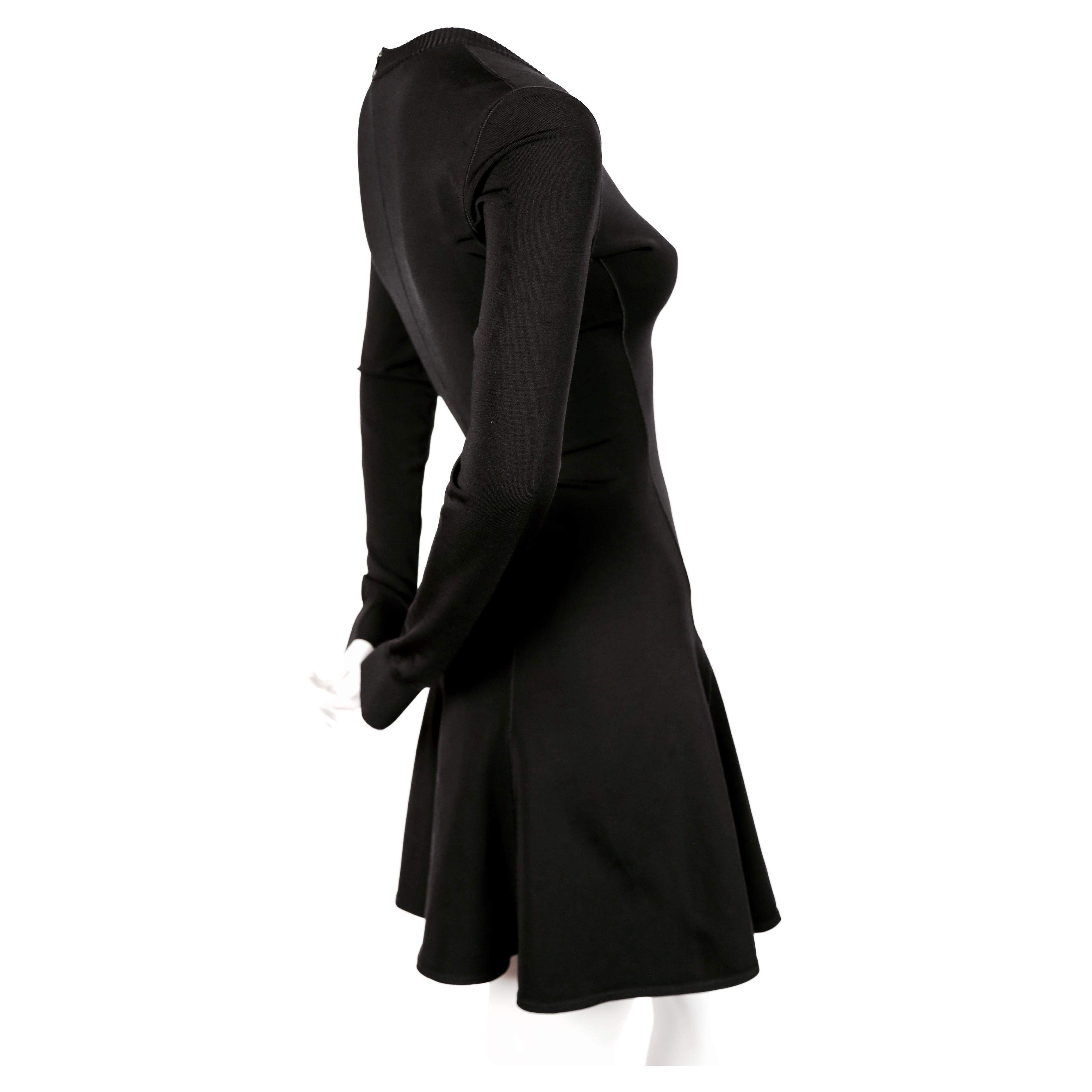 Jet black skater dress with V-neckline and long sleeves designed by Azzedine Alaia dating to the early 1990's. Size XS. Approximate measurements (unstretched): shoulder 14