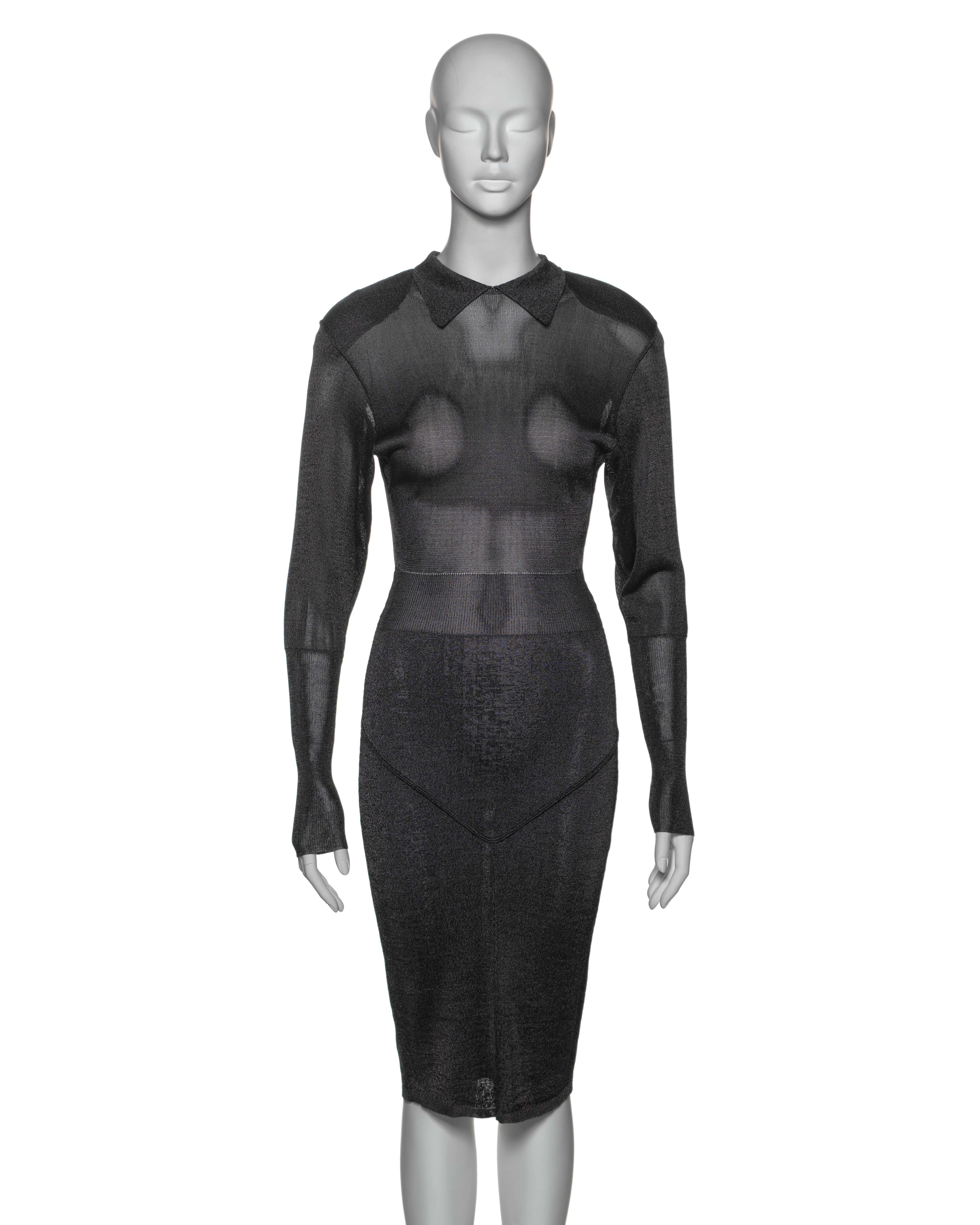 Questo primo abito di Azzedine Alaia è realizzato in viscosa lavorata a maglia color grigio antracite, che offre una texture leggera e semitrasparente. Il design prevede maniche lunghe con polsini allungati e colletto a punta. La silhouette attenta