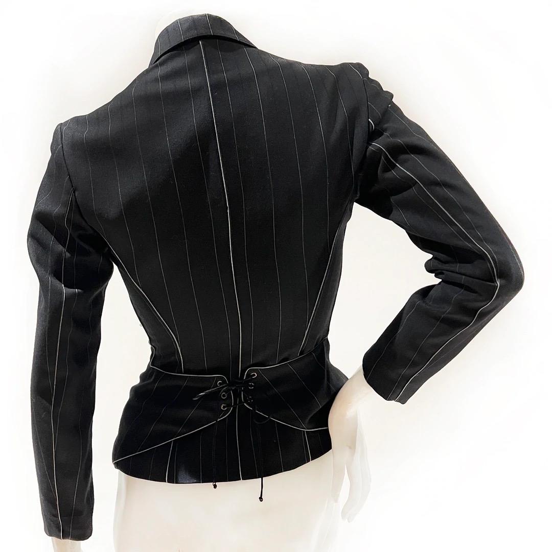 Azzedine Alaïa Fitted Jacket 
Fall / Winter 1990 Ready-to-Wear
Made in France 
Black 
Pinstripe 
Grey piping detail 
6 black buttons down front of jacket 
Notched lapel 
Back of the jacket has a laced corset detail 
Black silk lacing 
Interior of
