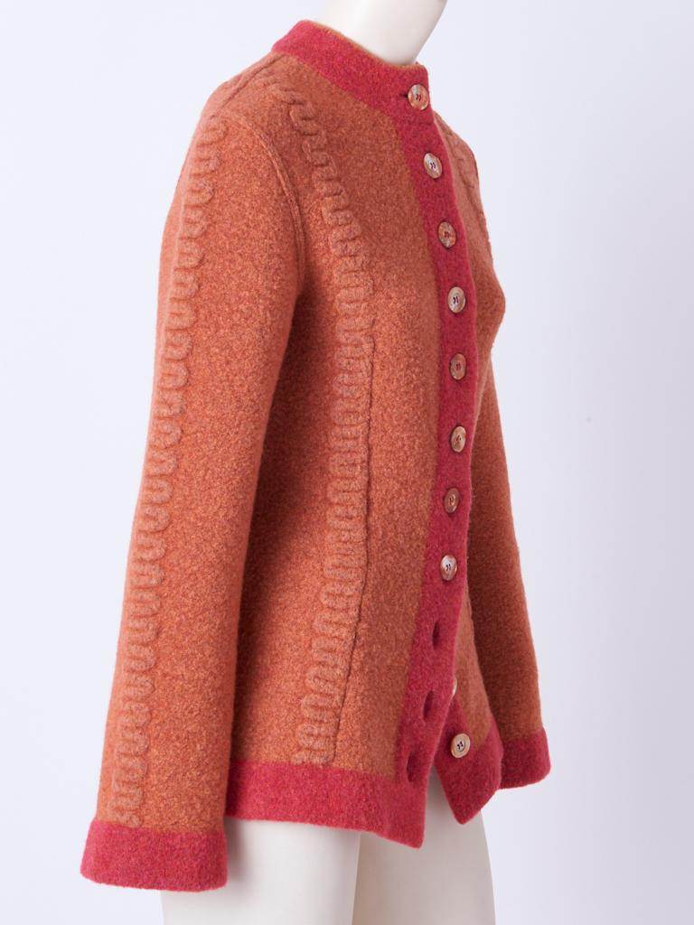 Azzedine Alaia, boiled wool, fitted cardigan in tones of coral, having a raised, pattern detail along the front and center sleeves. Mother of Pearl button closures.