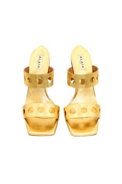 Mules de Azzedine Alaïa, de piel dorada con perforaciones, tacón metálico escultural y puntera cuadrada, talla 37